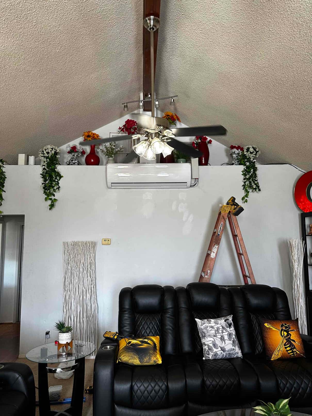 Indoor mini-split wall-mounted air handler installed above the living area, with ladder and tools visible during the installation.
