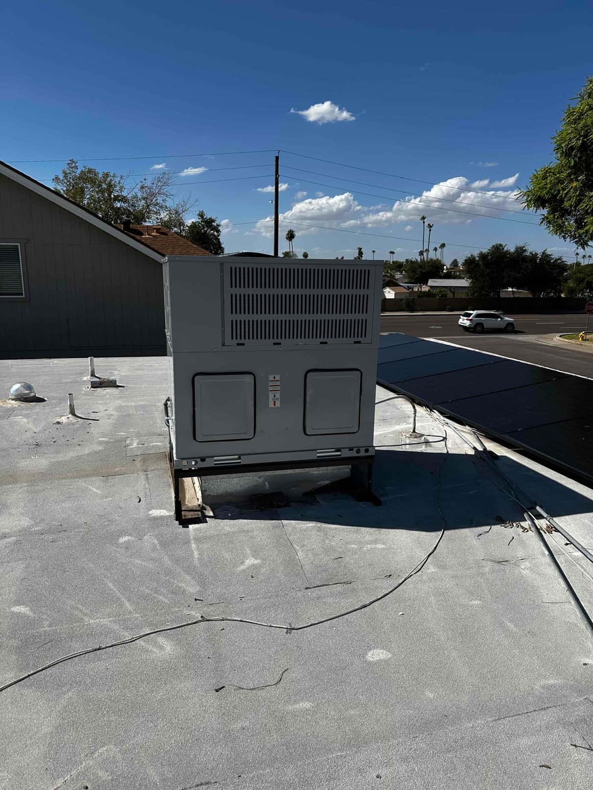 Rooftop HVAC package unit set on support rails with sealed roof penetrations visible around the installation area.