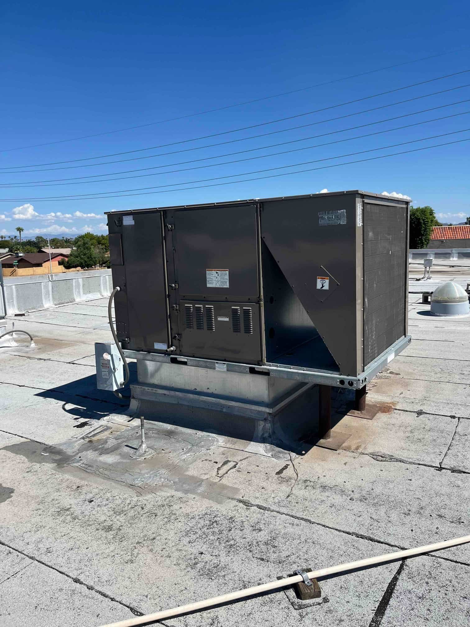 Rooftop packaged HVAC unit on a commercial building, showing exterior panels, service disconnect, and rooftop curb installation.