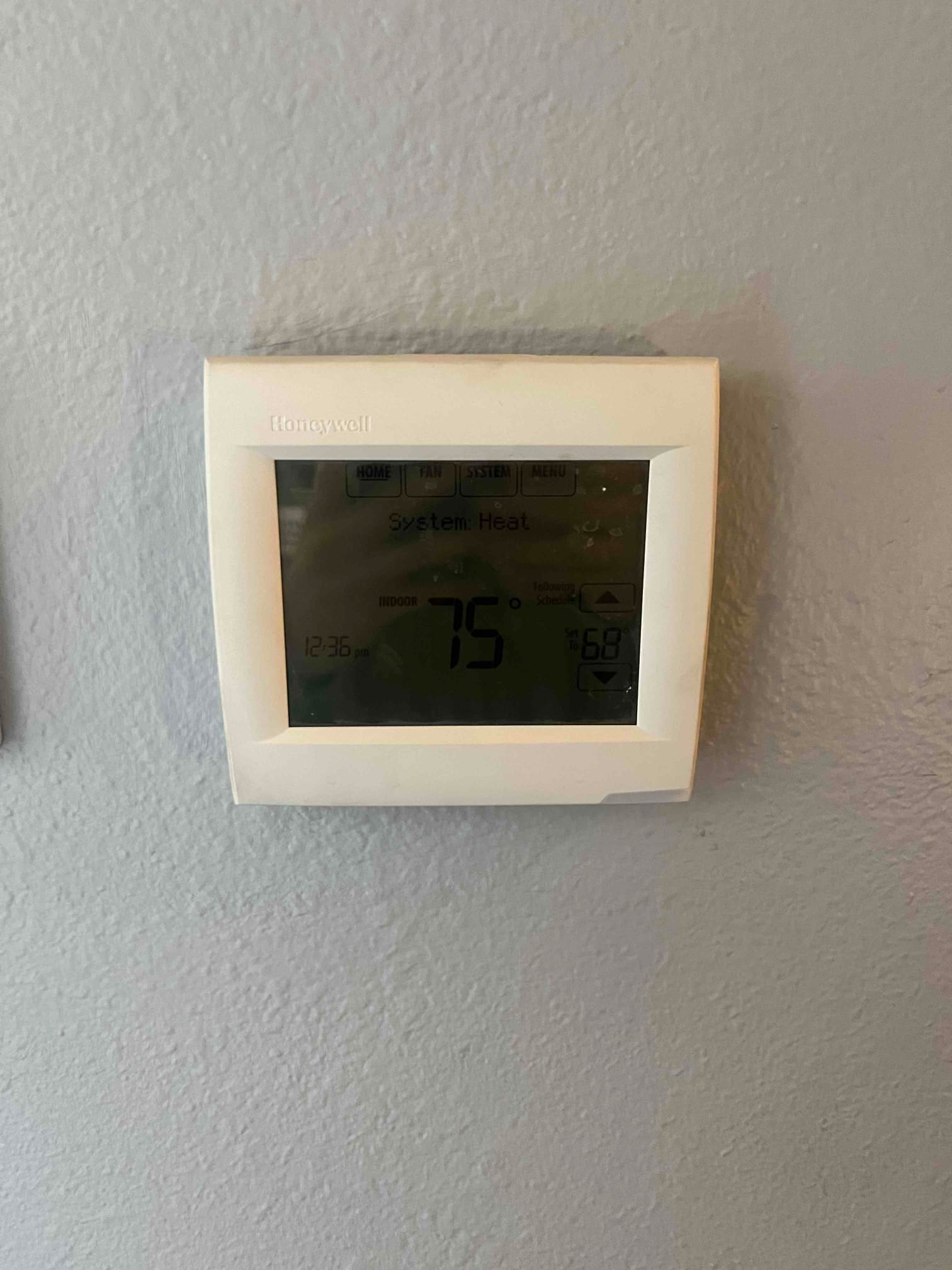Wall-mounted digital thermostat display shows system heat mode with a setpoint of 75 degrees and ambient reading visible.