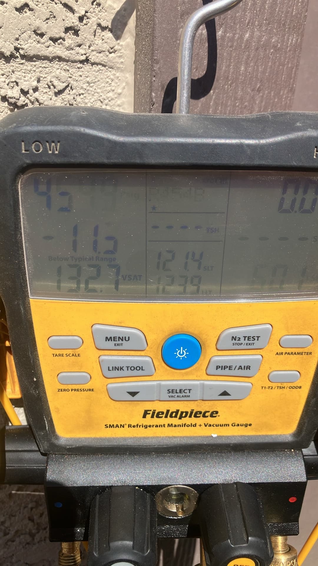 Digital manifold shows operating pressures with distinct low and high sides while the mini-split runs during commissioning.