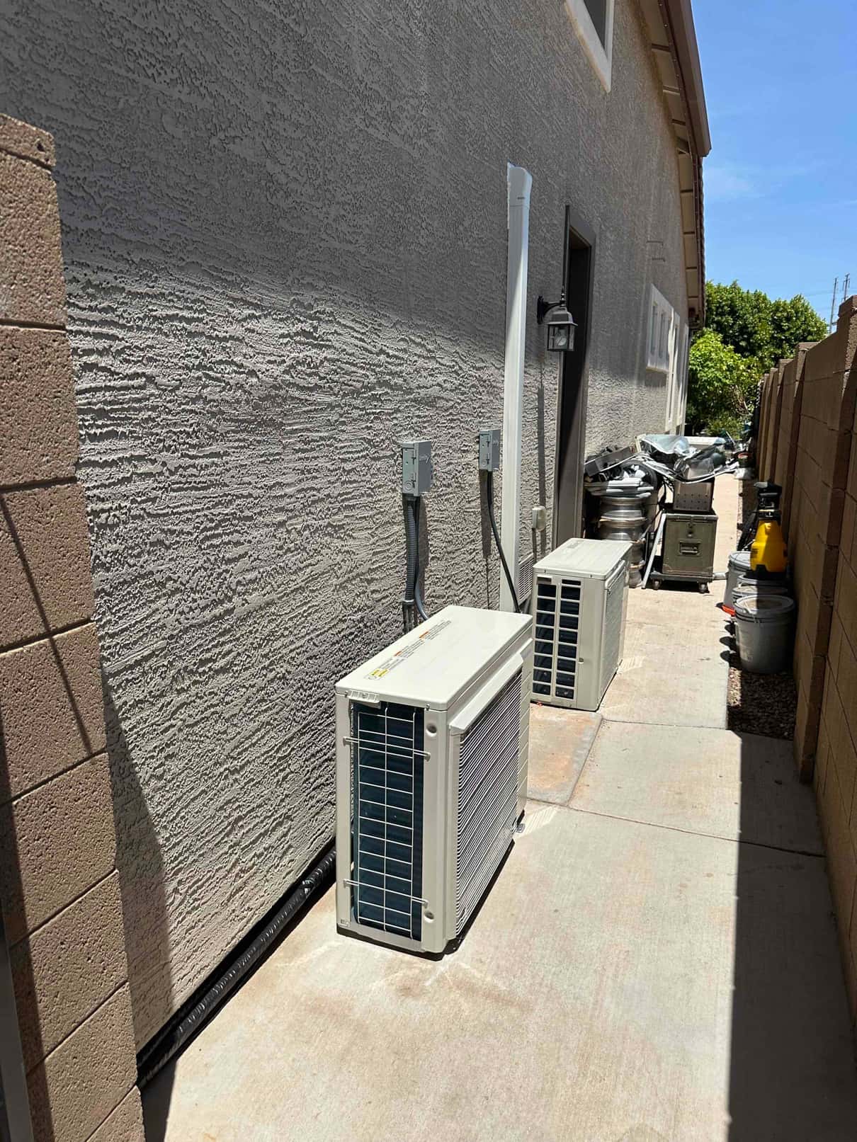 Two new mini-split outdoor units set on pads with mounted disconnects and covered line set along the exterior wall.