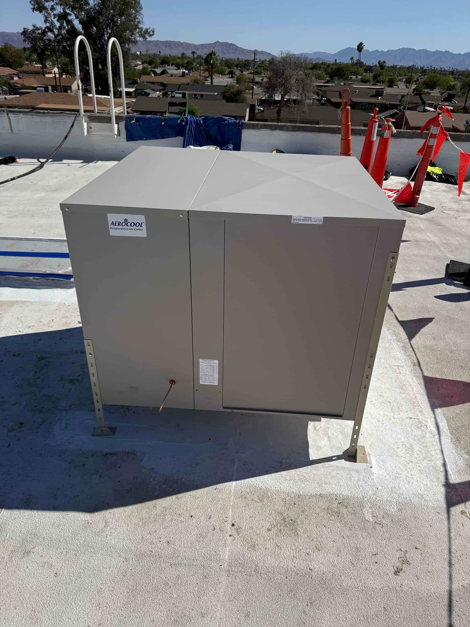 New rooftop evaporative cooler installed on stand-offs with sealed curb, shown during daylight on a flat roof.