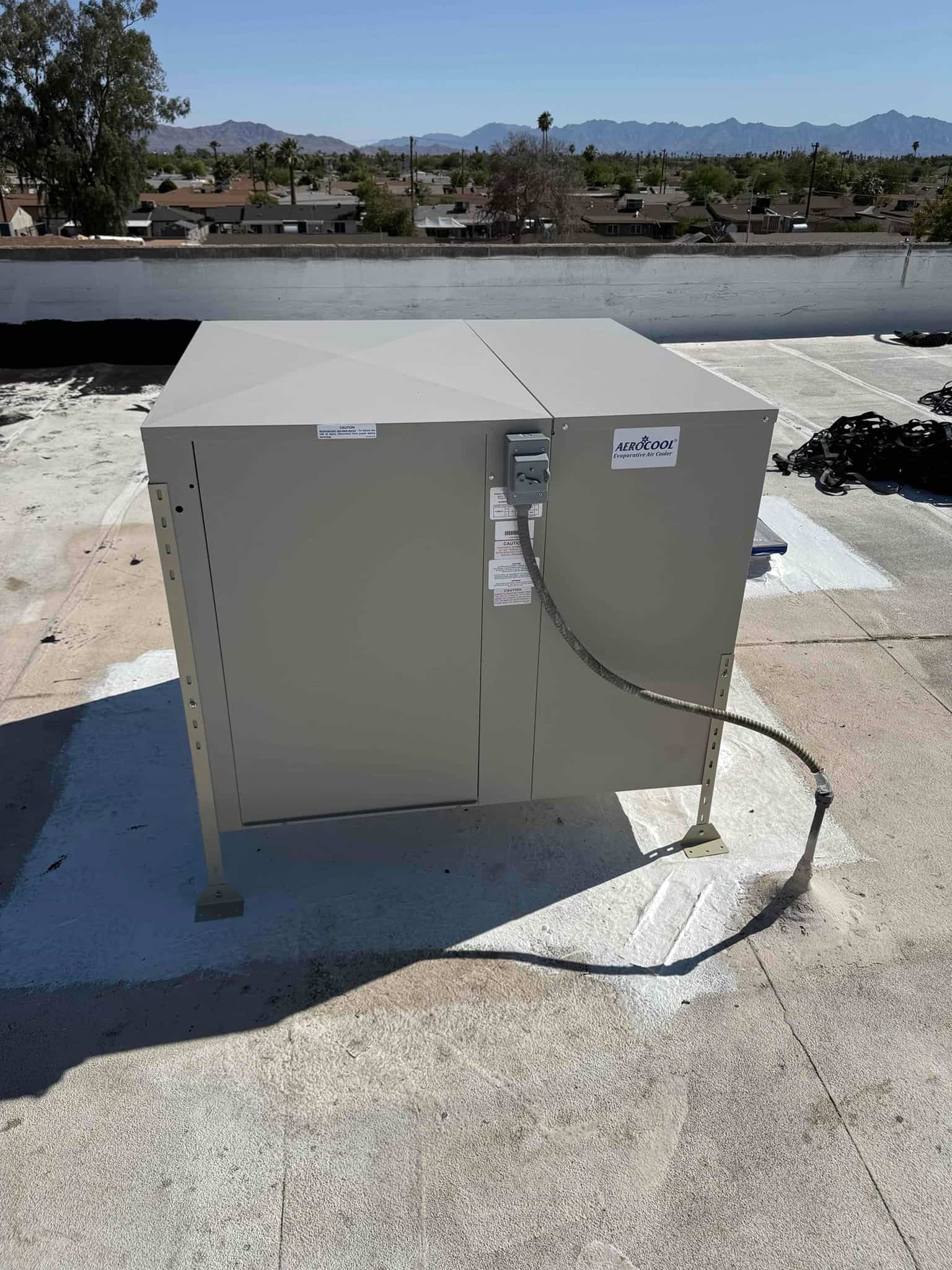 New rooftop evaporative cooler set on a sealed curb with electrical whip connected at the service disconnect.