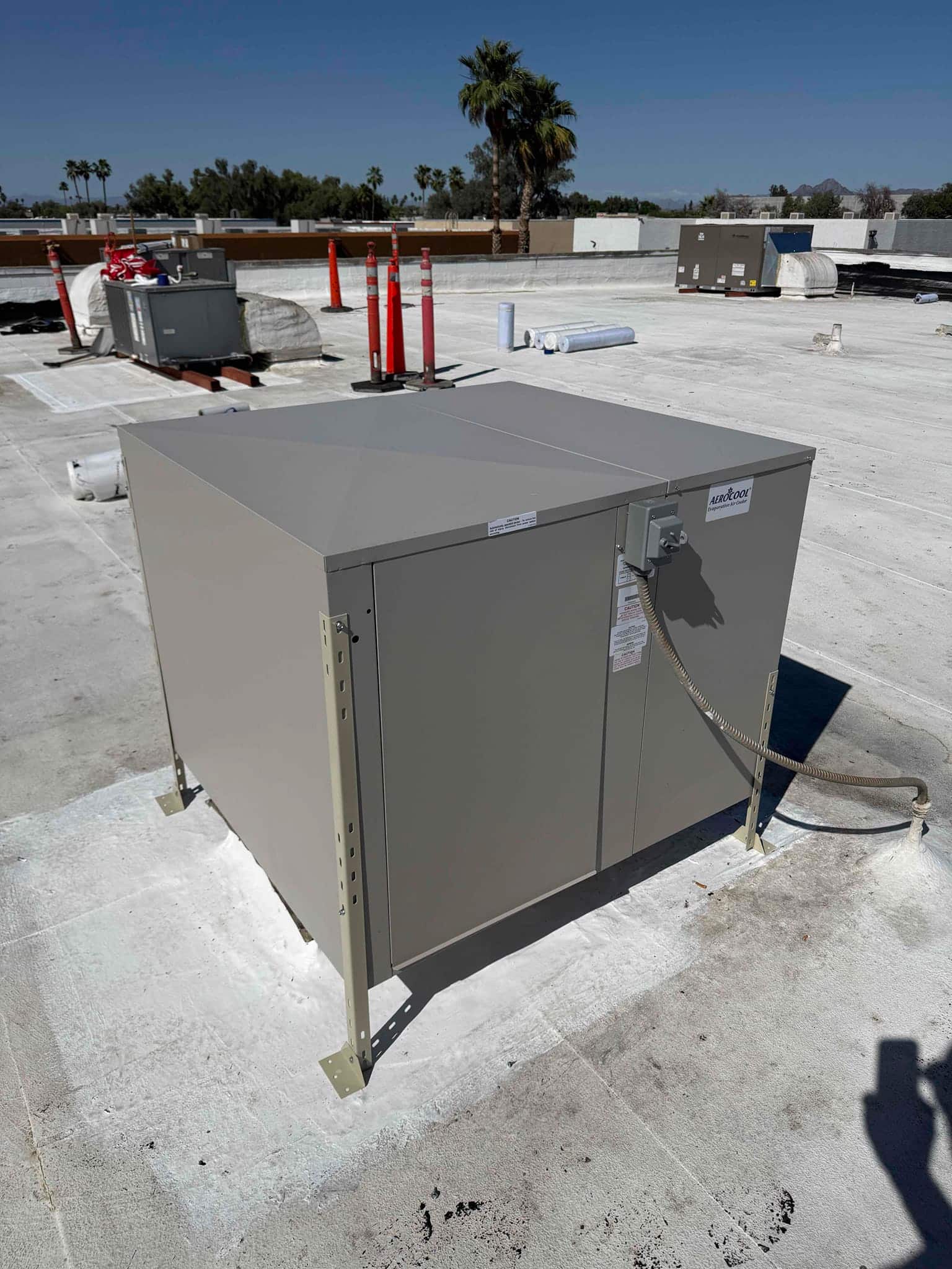 New rooftop HVAC unit installed on raised stands with sealed roof penetrations and flexible electrical conduit connected.