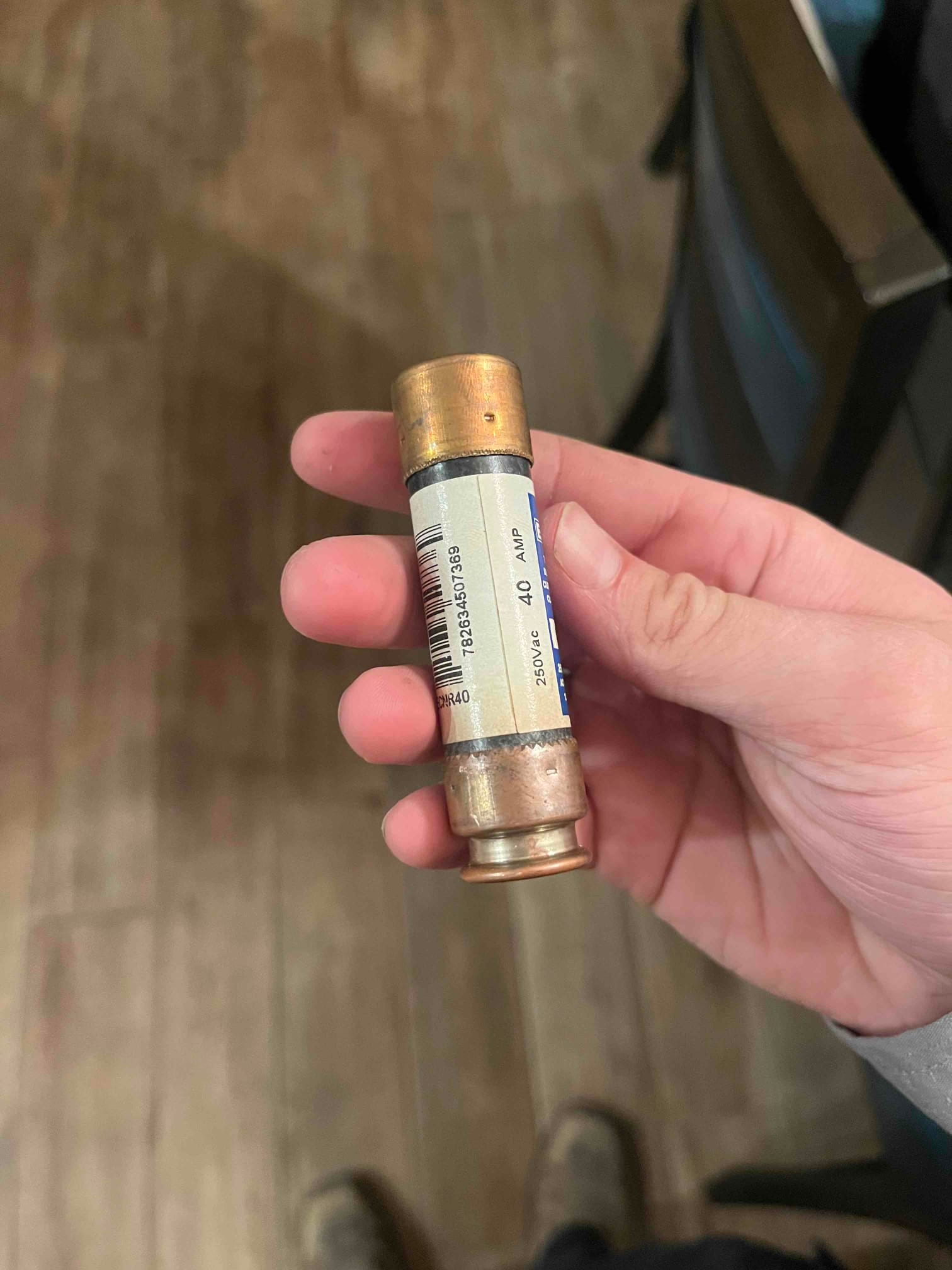 Cartridge fuse with copper end caps held in hand; label shows 40 AMP, 250V rating.