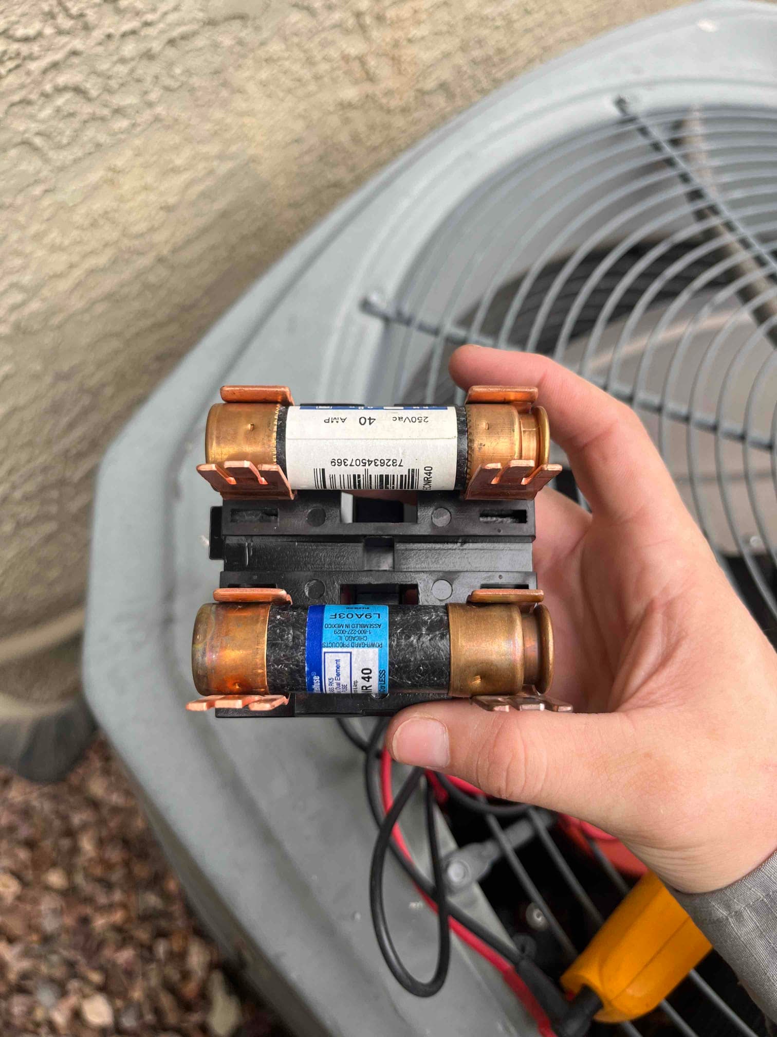 Two cartridge fuses rated 40 amp held in a fuse holder near an outdoor condenser fan unit.