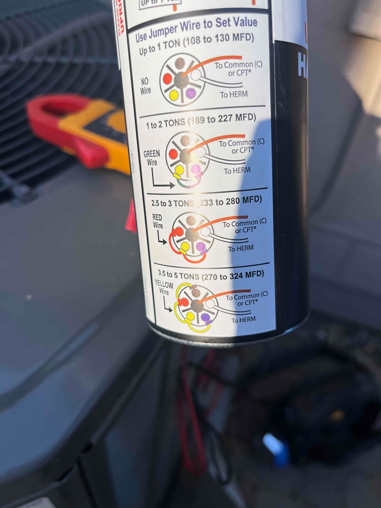 Hard-start capacitor can with printed jumper wire instructions and MFD ranges for 1 to 5 ton systems.