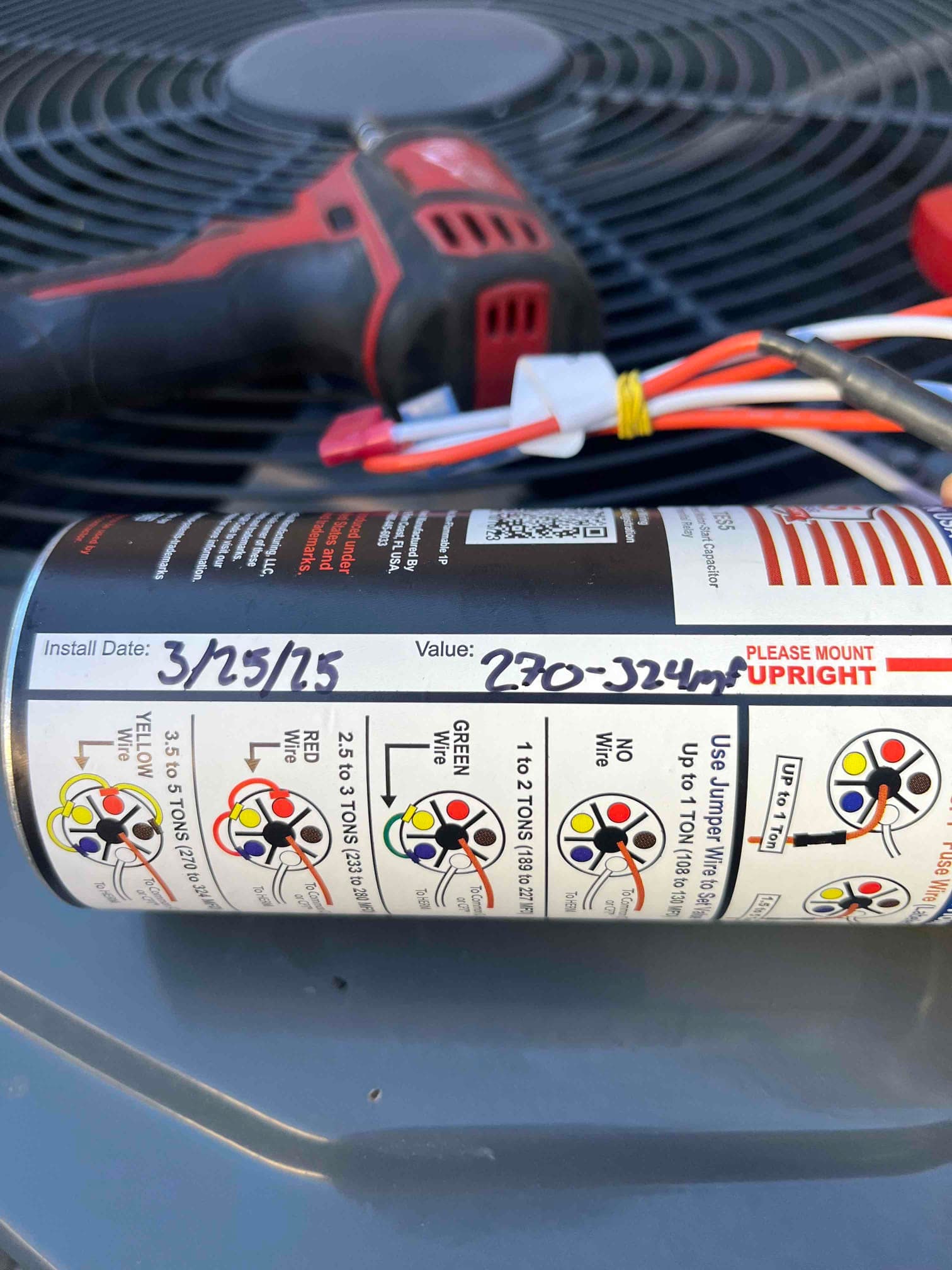 Hard-start capacitor on condenser top showing color wiring diagram, with handwritten Install Date 3/25/25 and Value 270-324 μF on label.