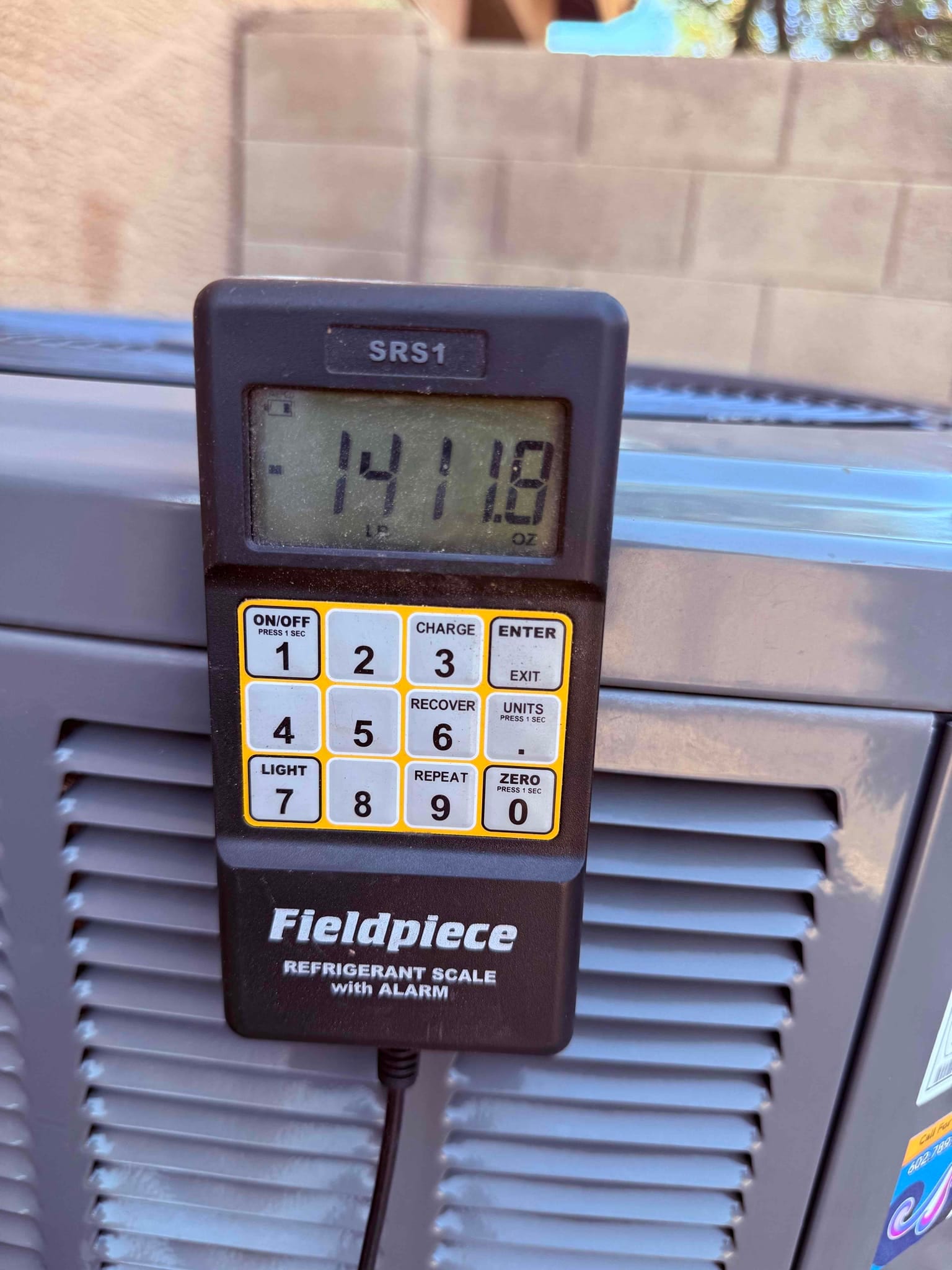 Refrigerant scale photographed during the service visit; no numerical reading is transcribed.