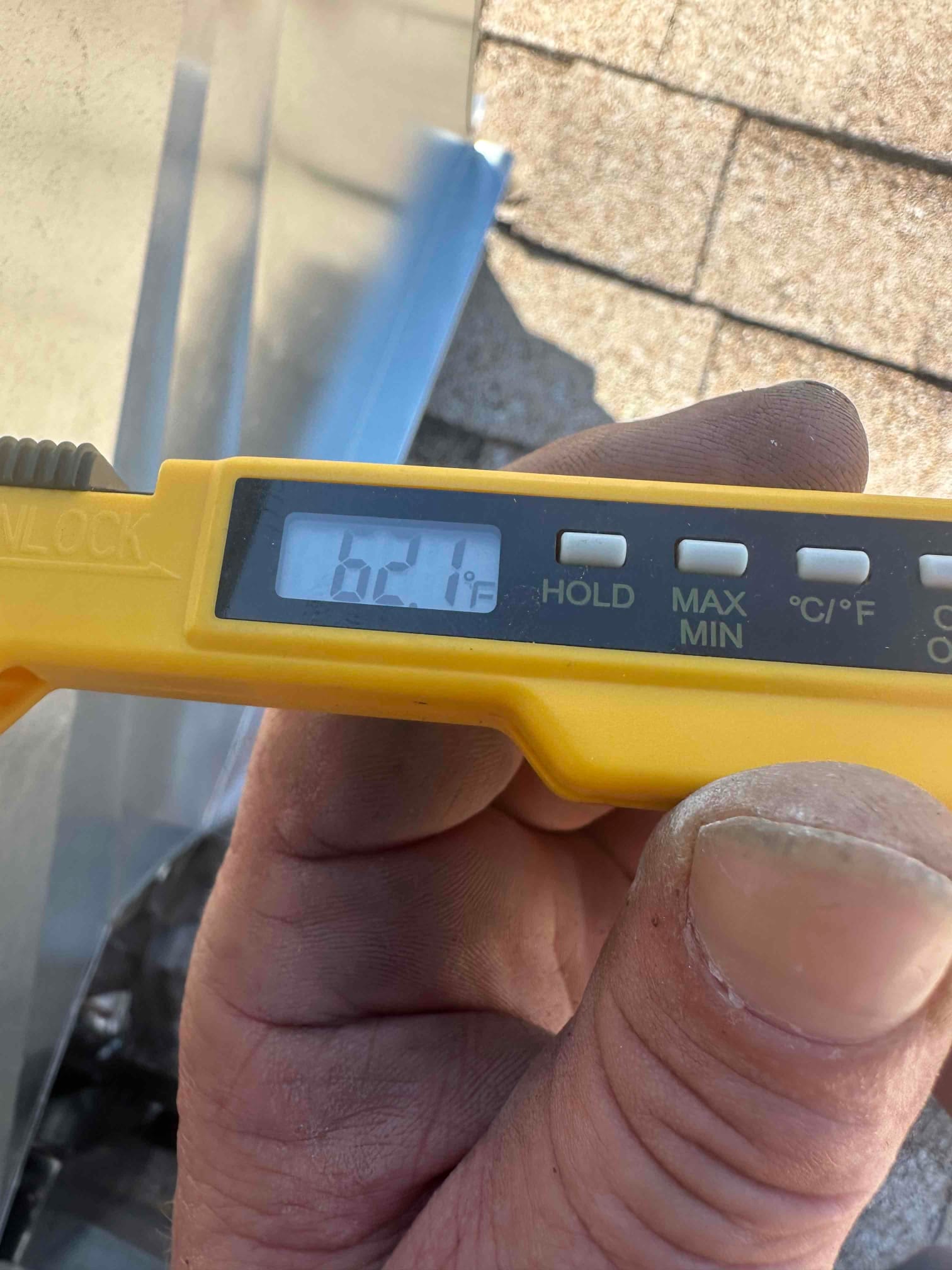 Digital thermometer shows 62.1°F while measuring air temperature during HVAC commissioning.