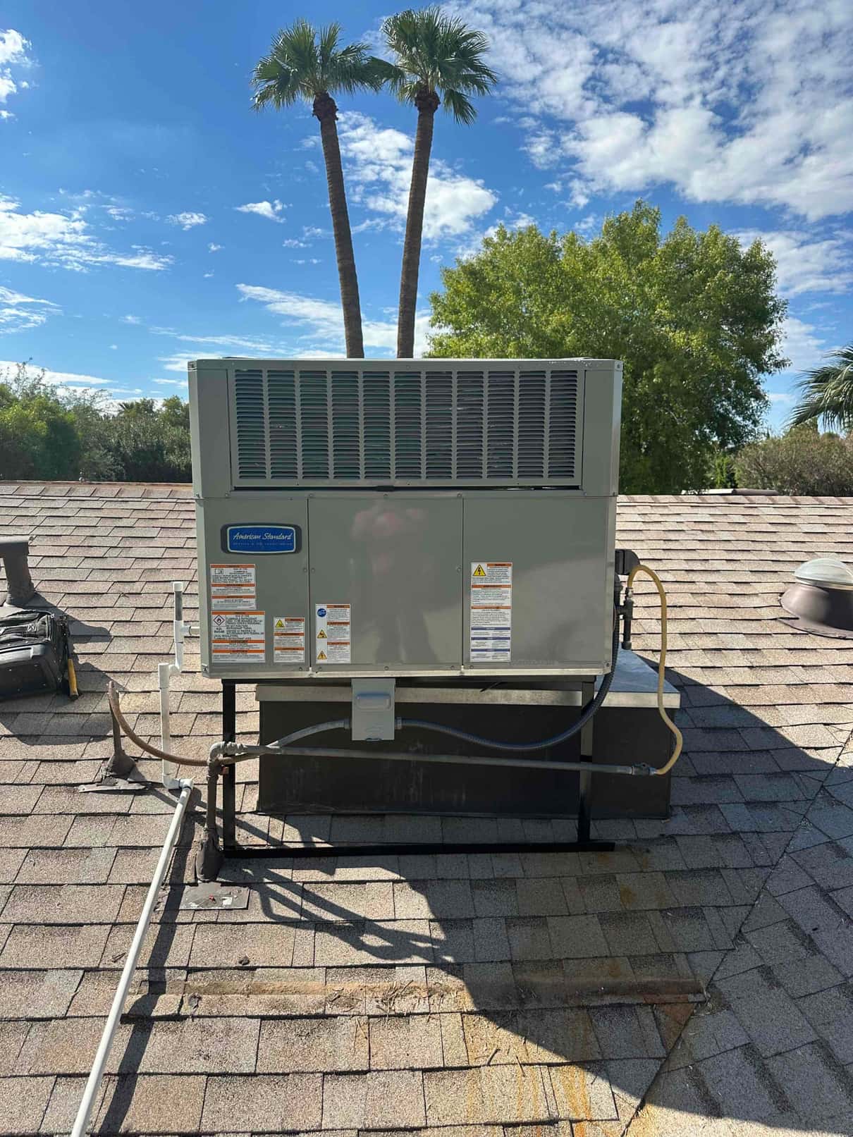 New rooftop package HVAC unit installed on curb with electrical disconnect, condensate drain, and sealed roof penetrations visible.