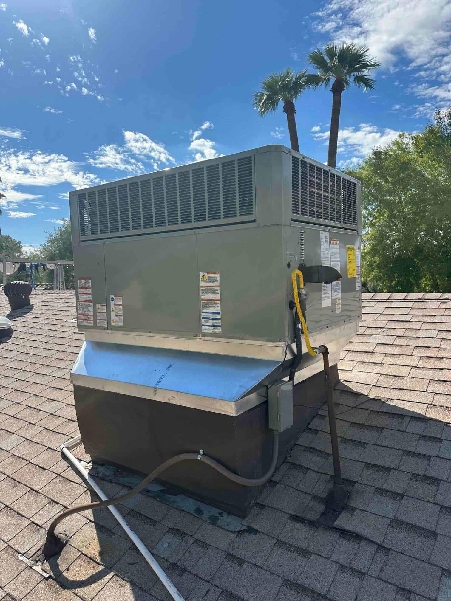New rooftop package HVAC unit set on a curb with sealed duct transition, electrical disconnect, and gas line connection visible.