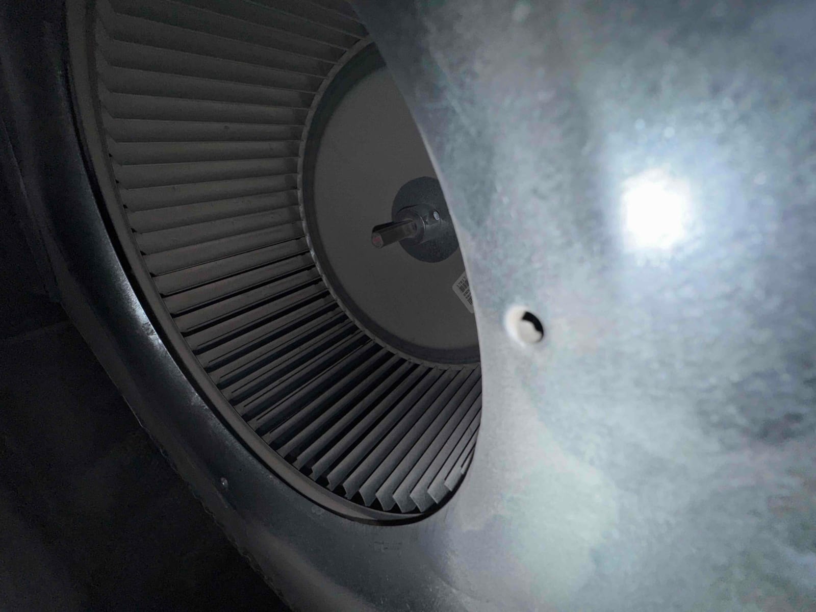 Close-up of a residential HVAC blower wheel inside the air handler housing, with vanes and motor hub visible.