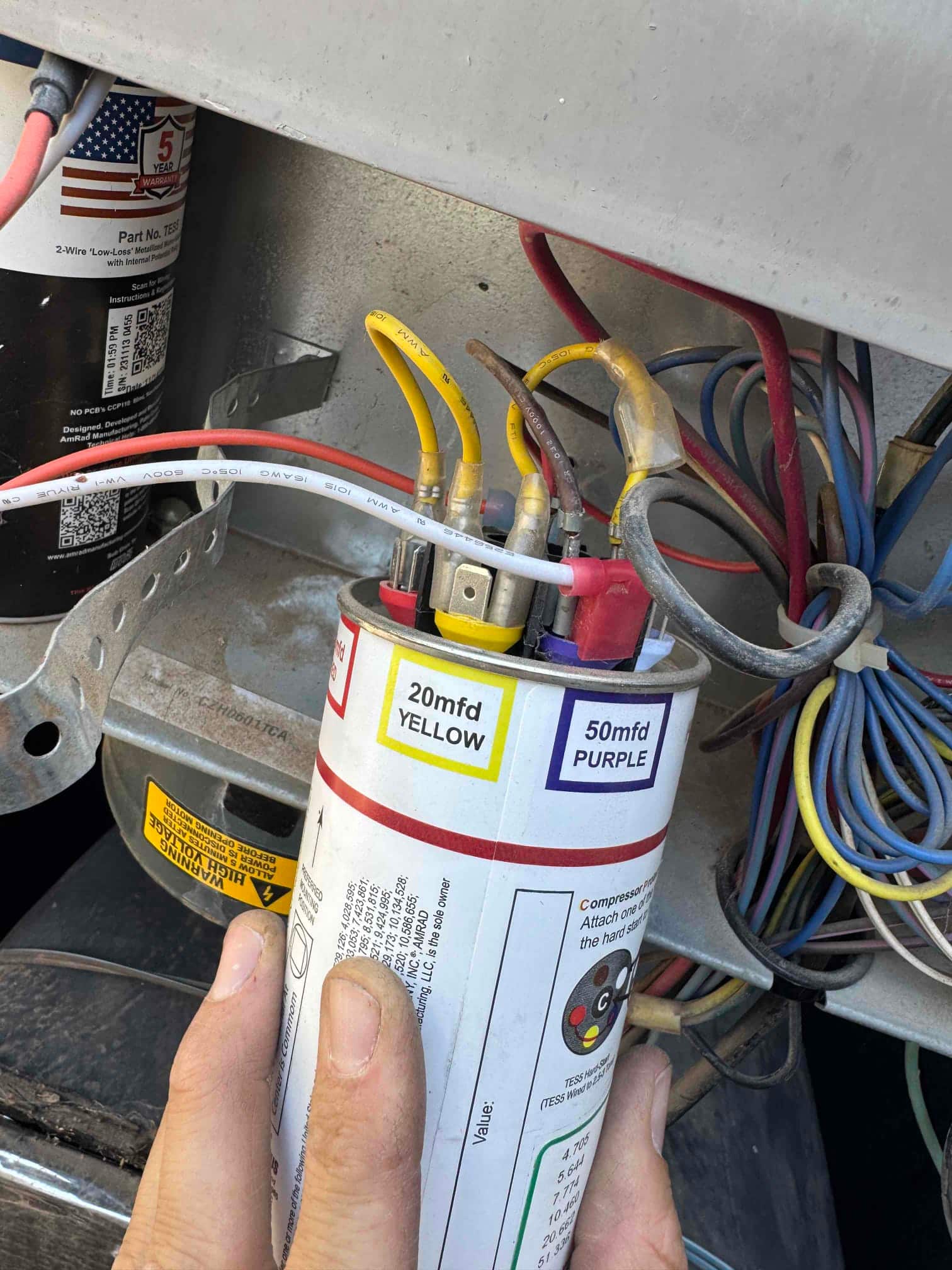 Dual-run capacitor labeled 20 mfd yellow and 50 mfd purple with wiring connected to terminals.