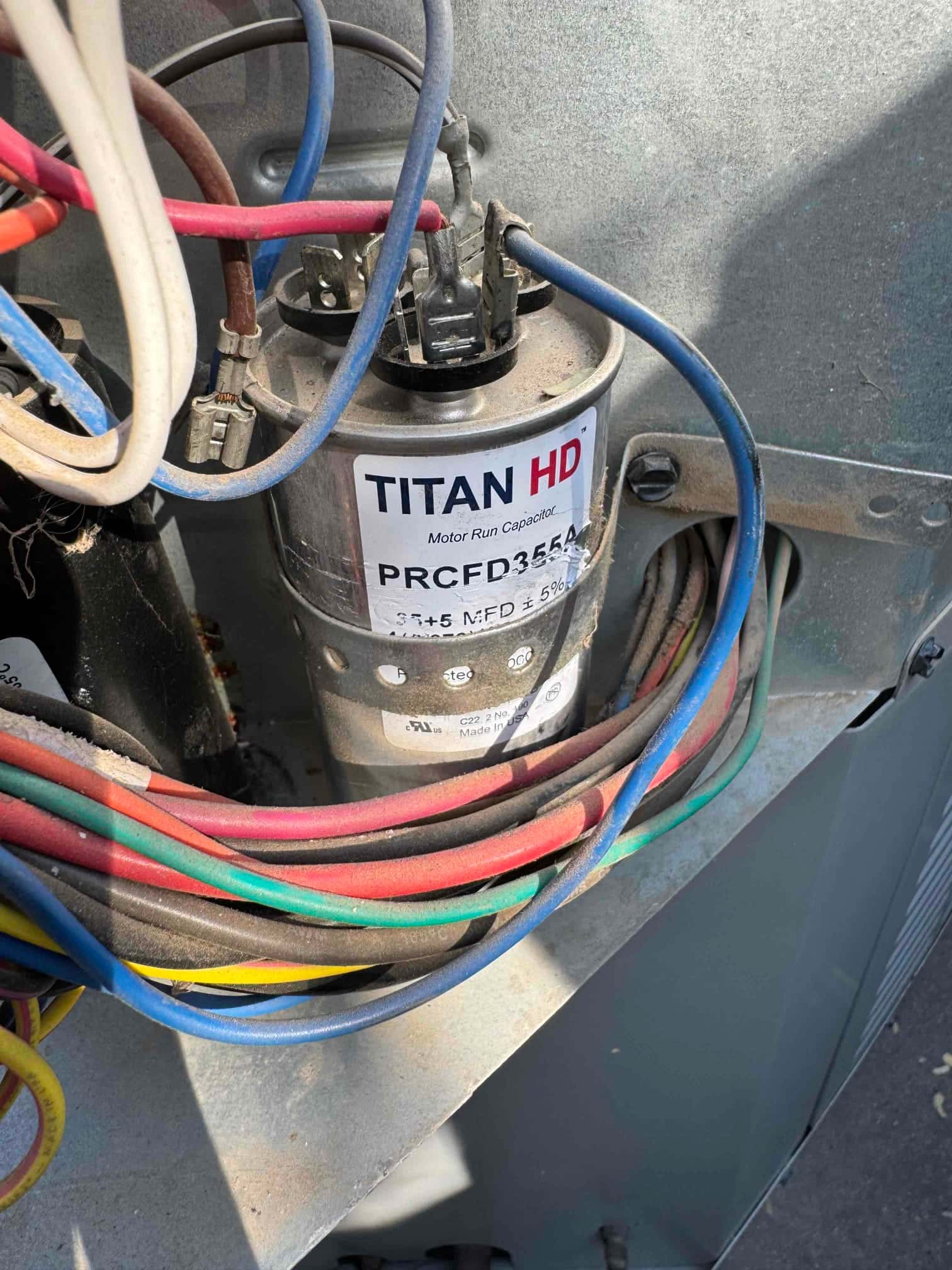 Dual-run capacitor labeled 35+5 MFD ±5% with multiple wires connected to its terminals inside the outdoor unit.
