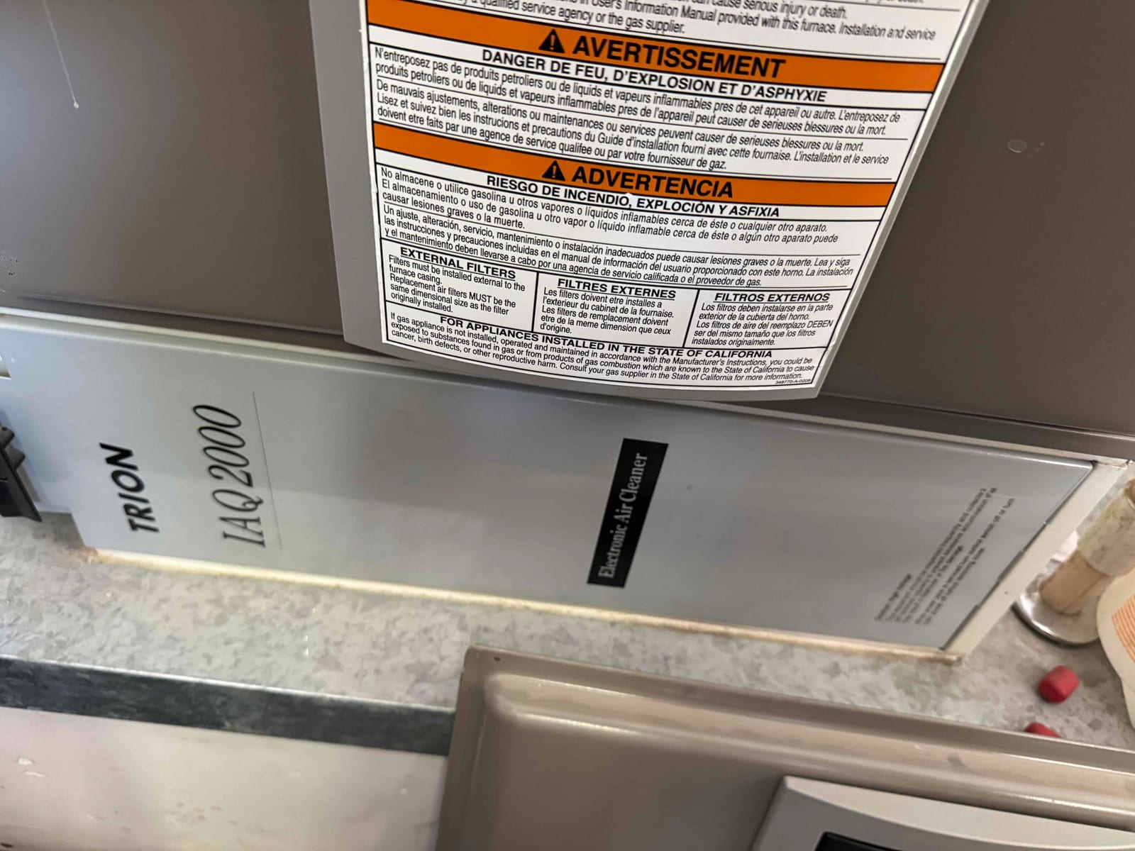 Electronic air cleaner cabinet below the furnace housing, with a large safety warning label and service panel visible.