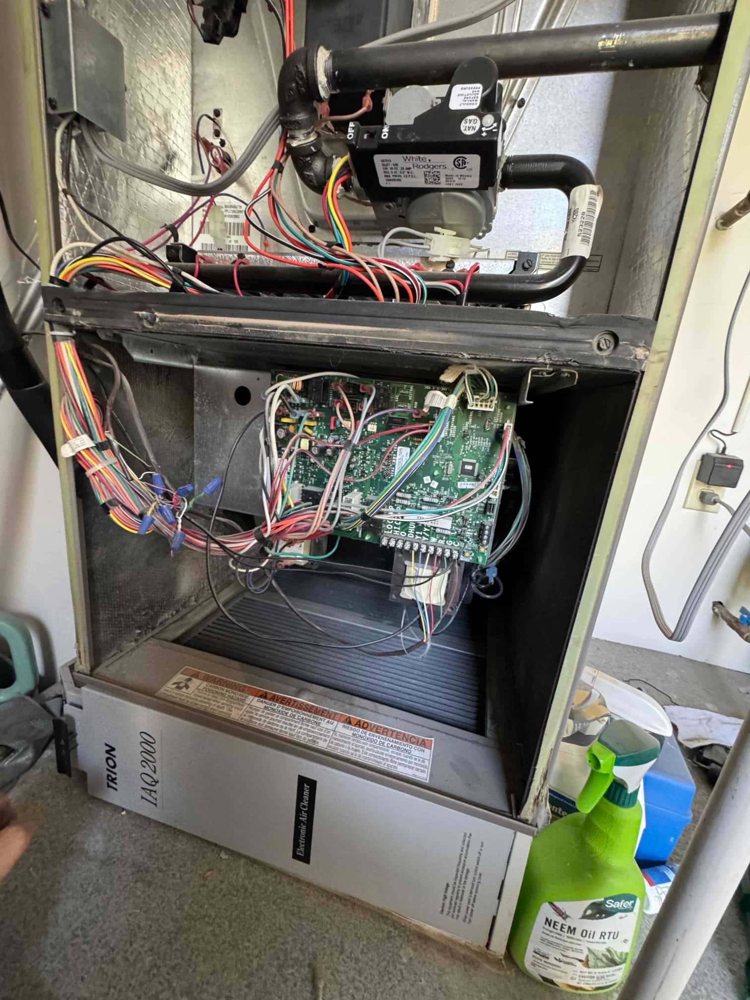 Open furnace cabinet shows control board with connected wiring, draft inducer assembly, and evaporator coil housing.