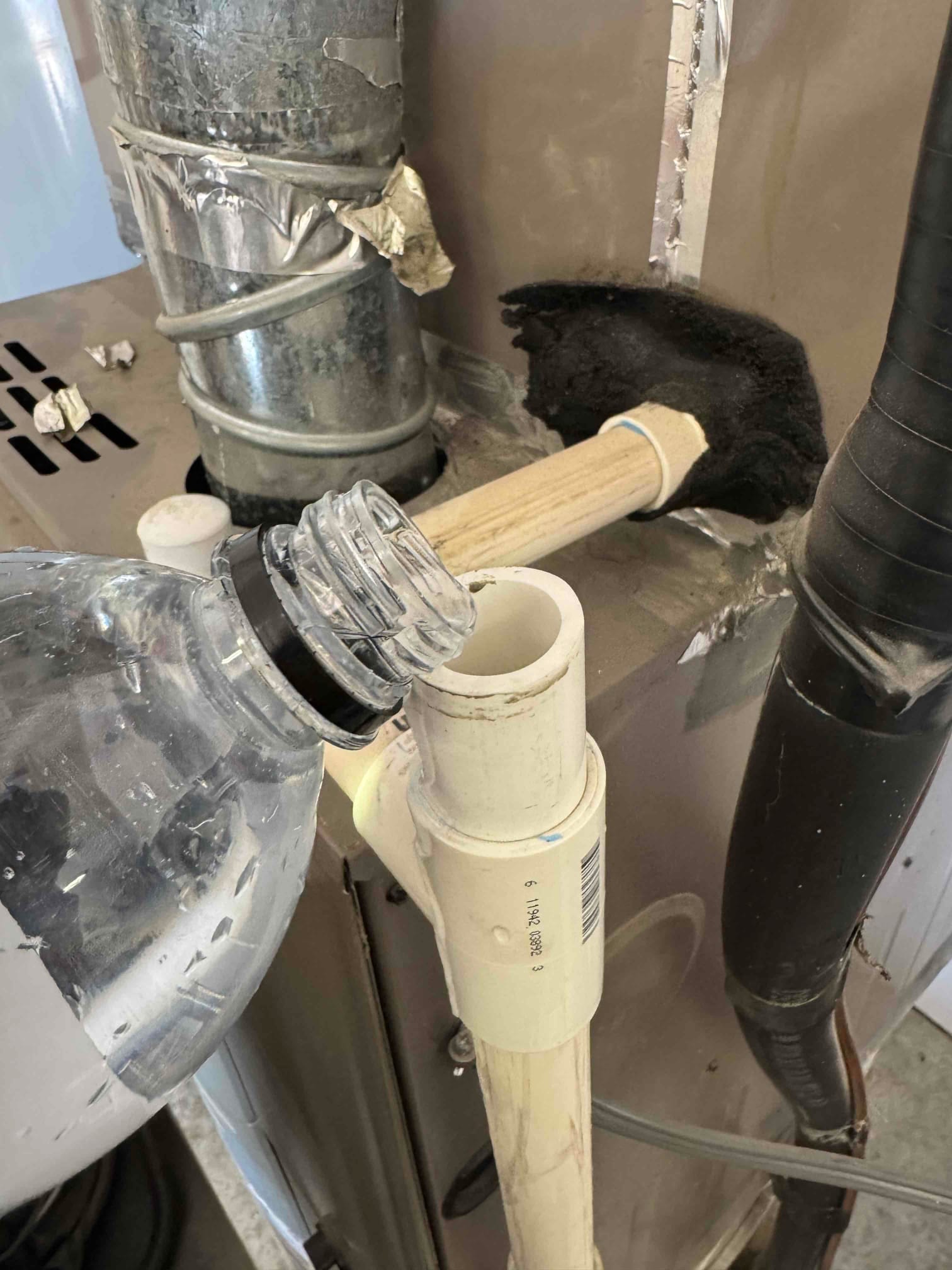 Open PVC condensate drain tee at air handler, water poured from bottle into line.