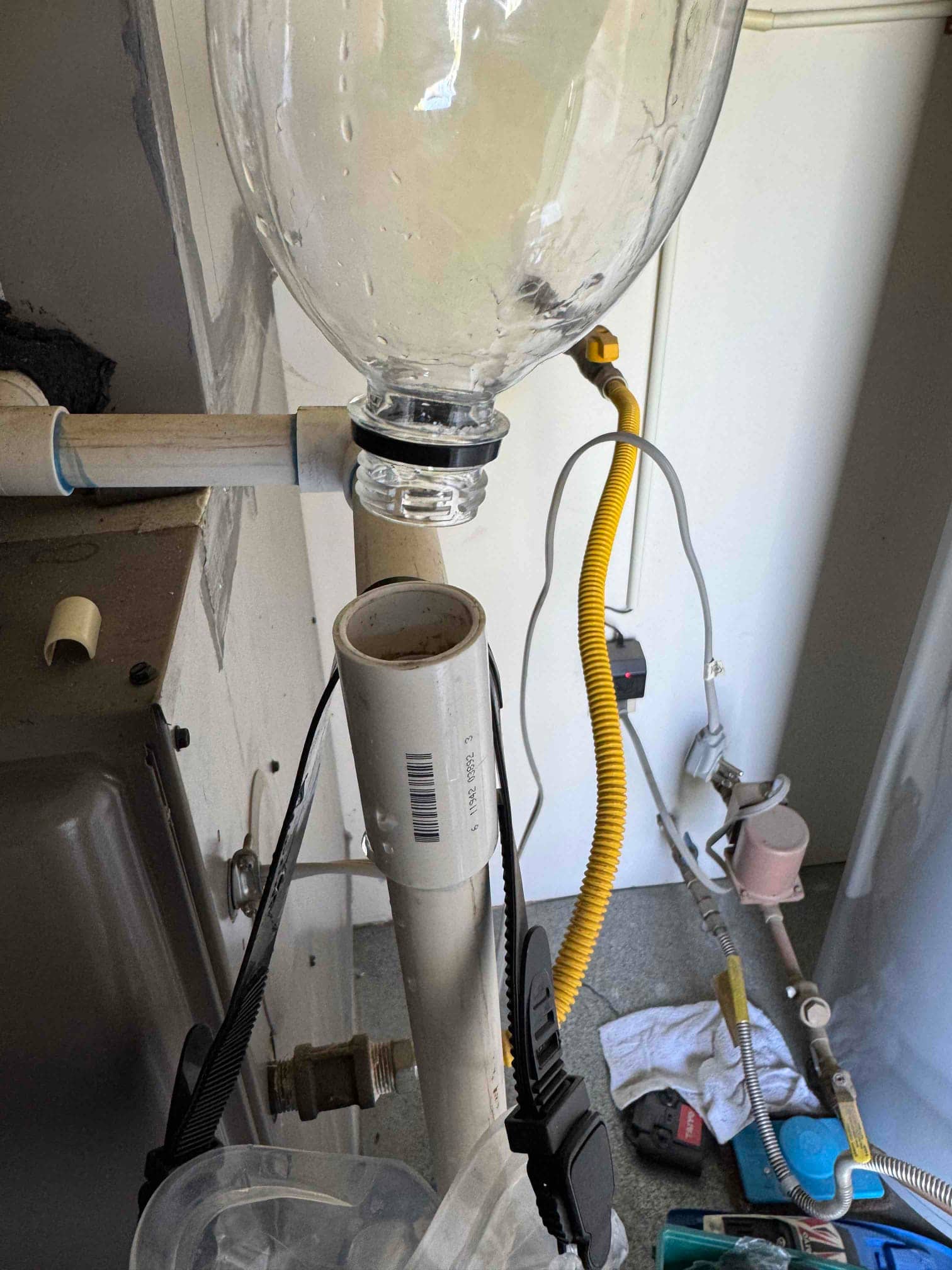 PVC condensate drain with open cleanout and improvised plastic bottle funnel attached for flushing.