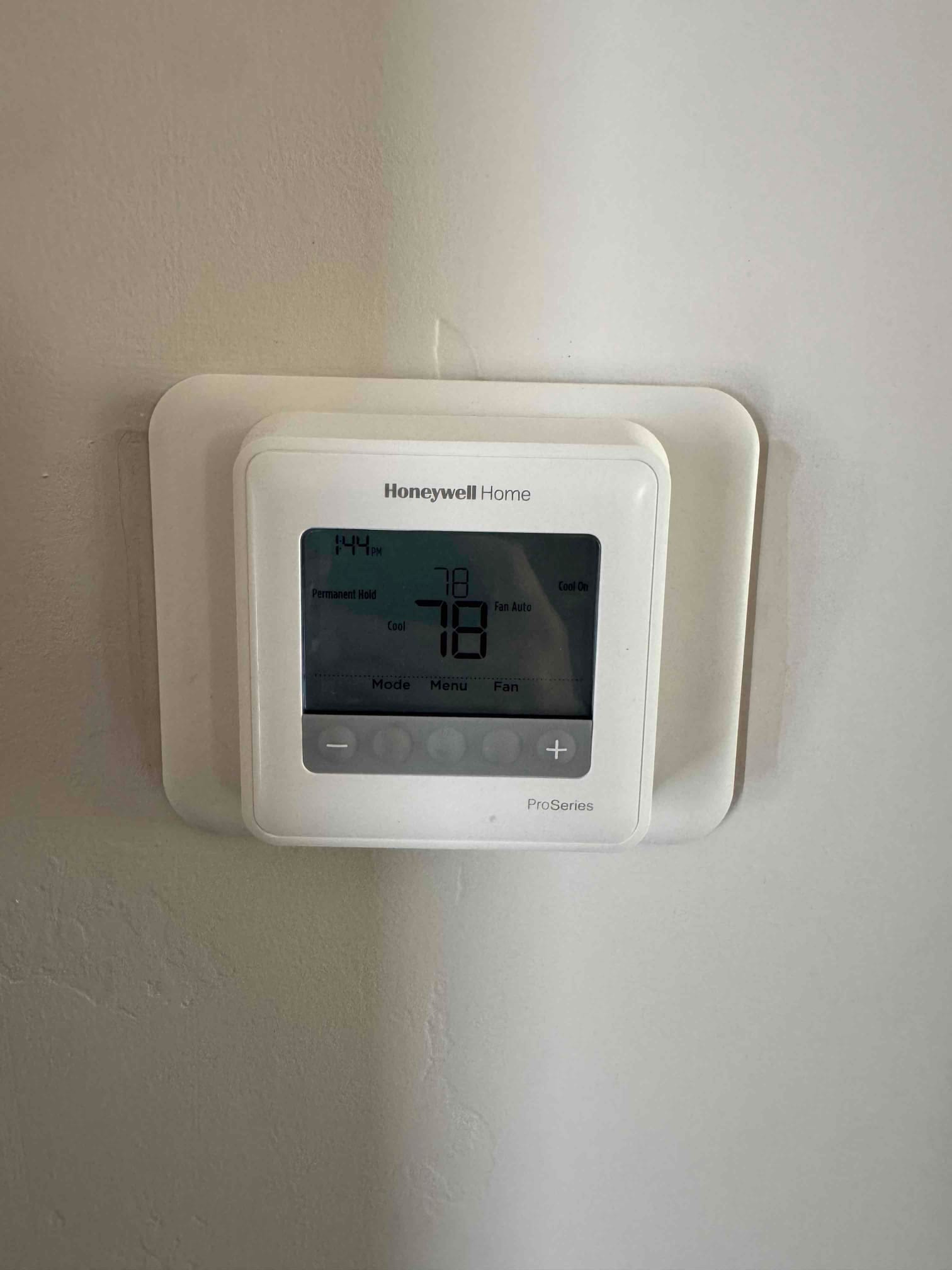 Wall-mounted digital thermostat with backplate; screen shows 1:44 PM, set to 78°F, Cool On, fan Auto.