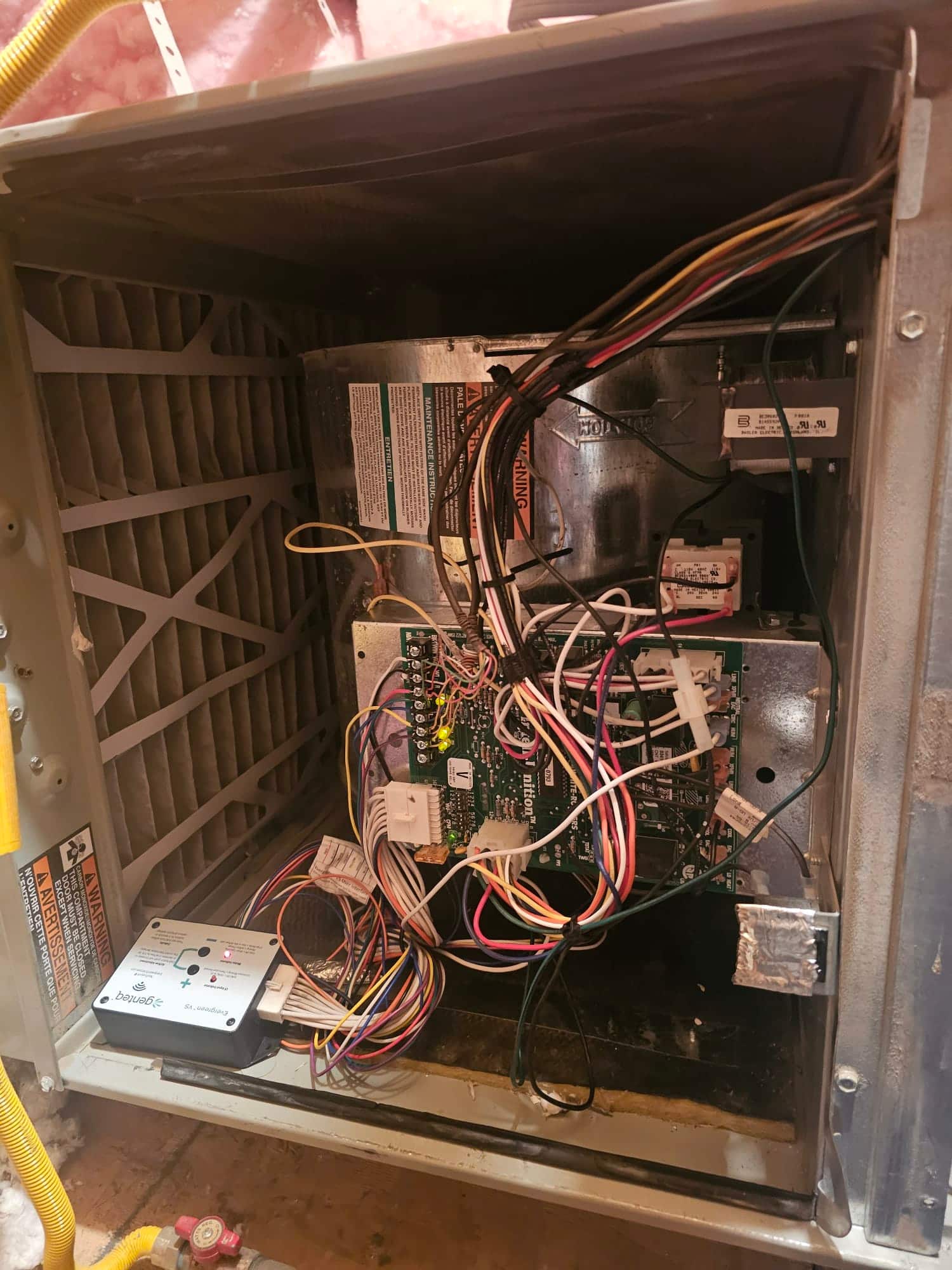Air handler blower compartment open, showing control board with connected wiring harnesses, blower housing, and pleated air filter.