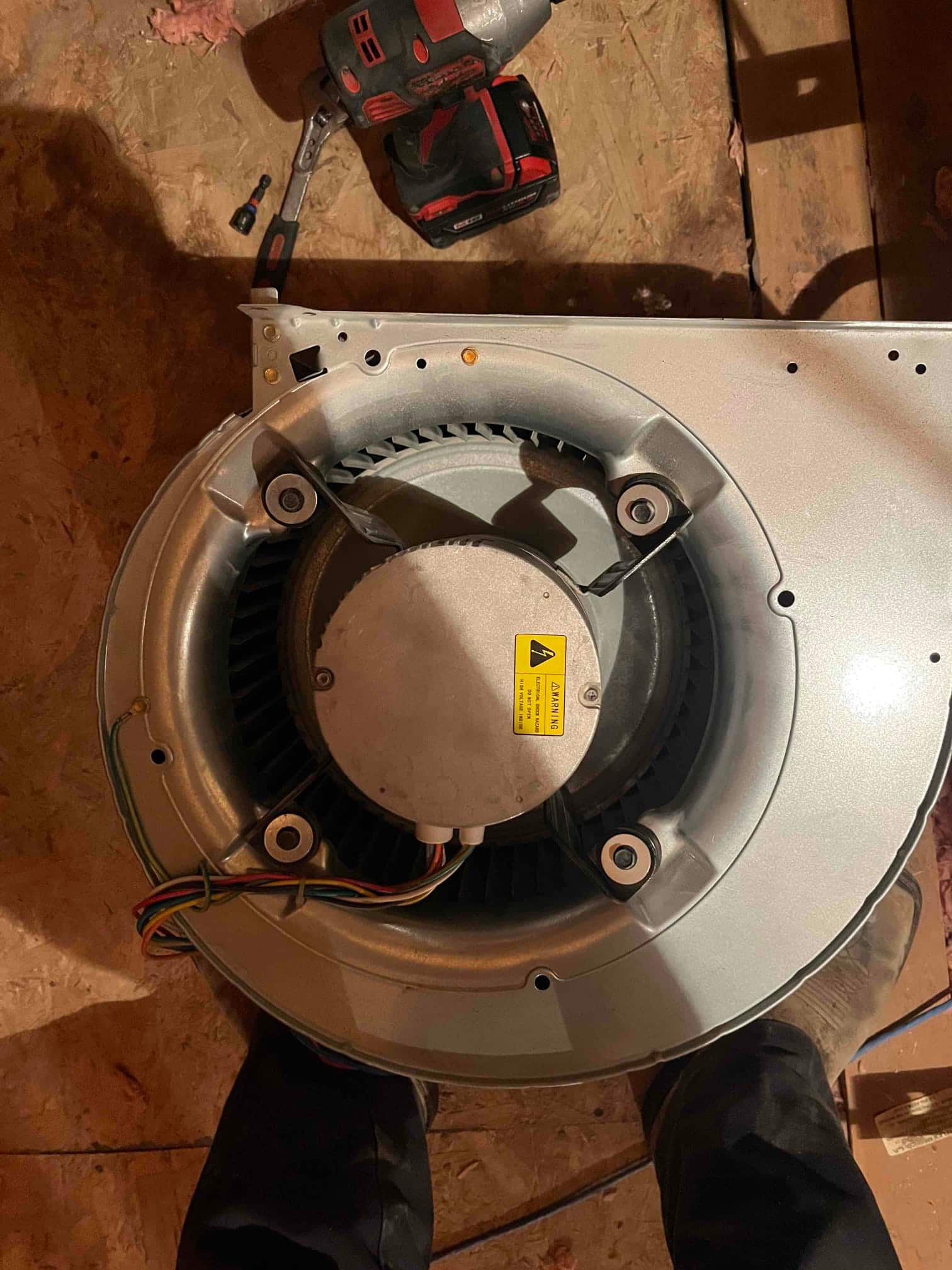 Blower assembly removed, showing centrifugal blower wheel, motor housing, and wiring harness on the floor.