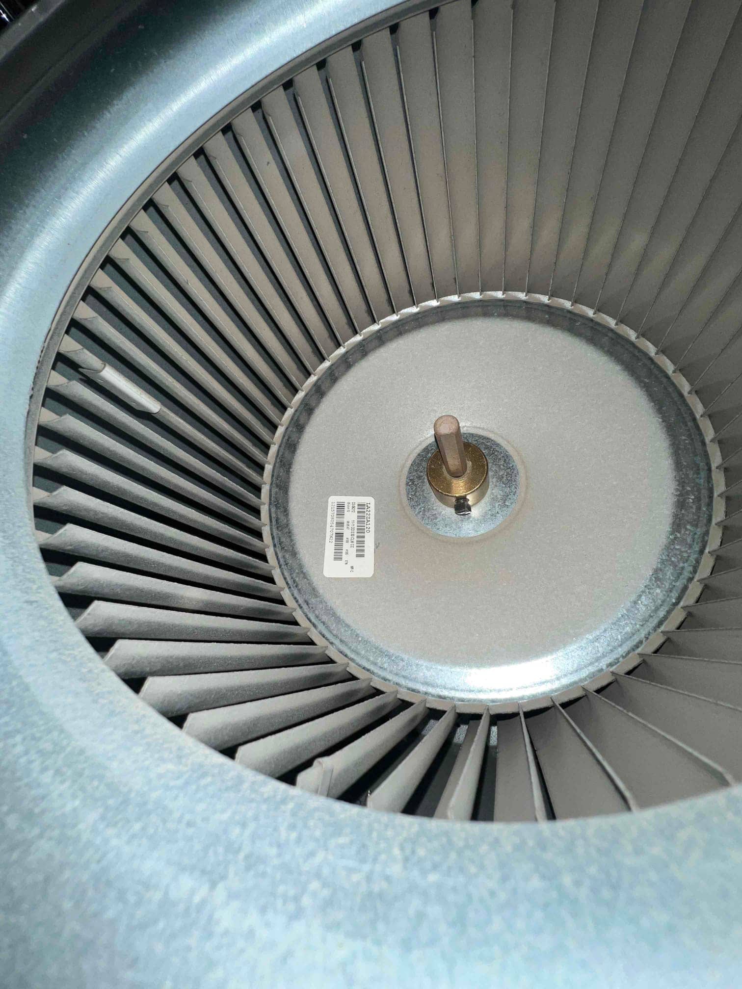 Centrifugal blower wheel with metal fins and a central hub, light dust visible on blades.