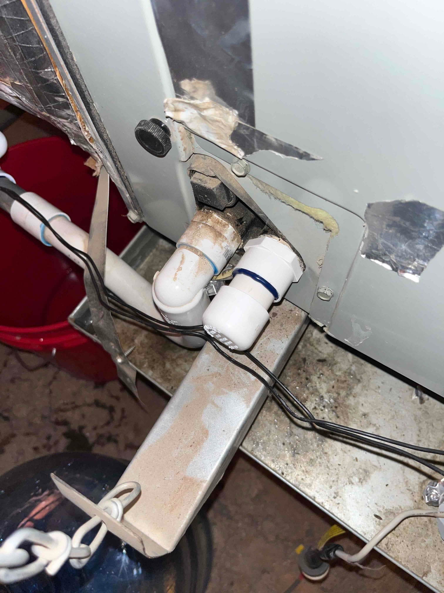 Condensate drain lines at indoor unit with PVC fittings and unions, wiring routed along the pipes and metal support.