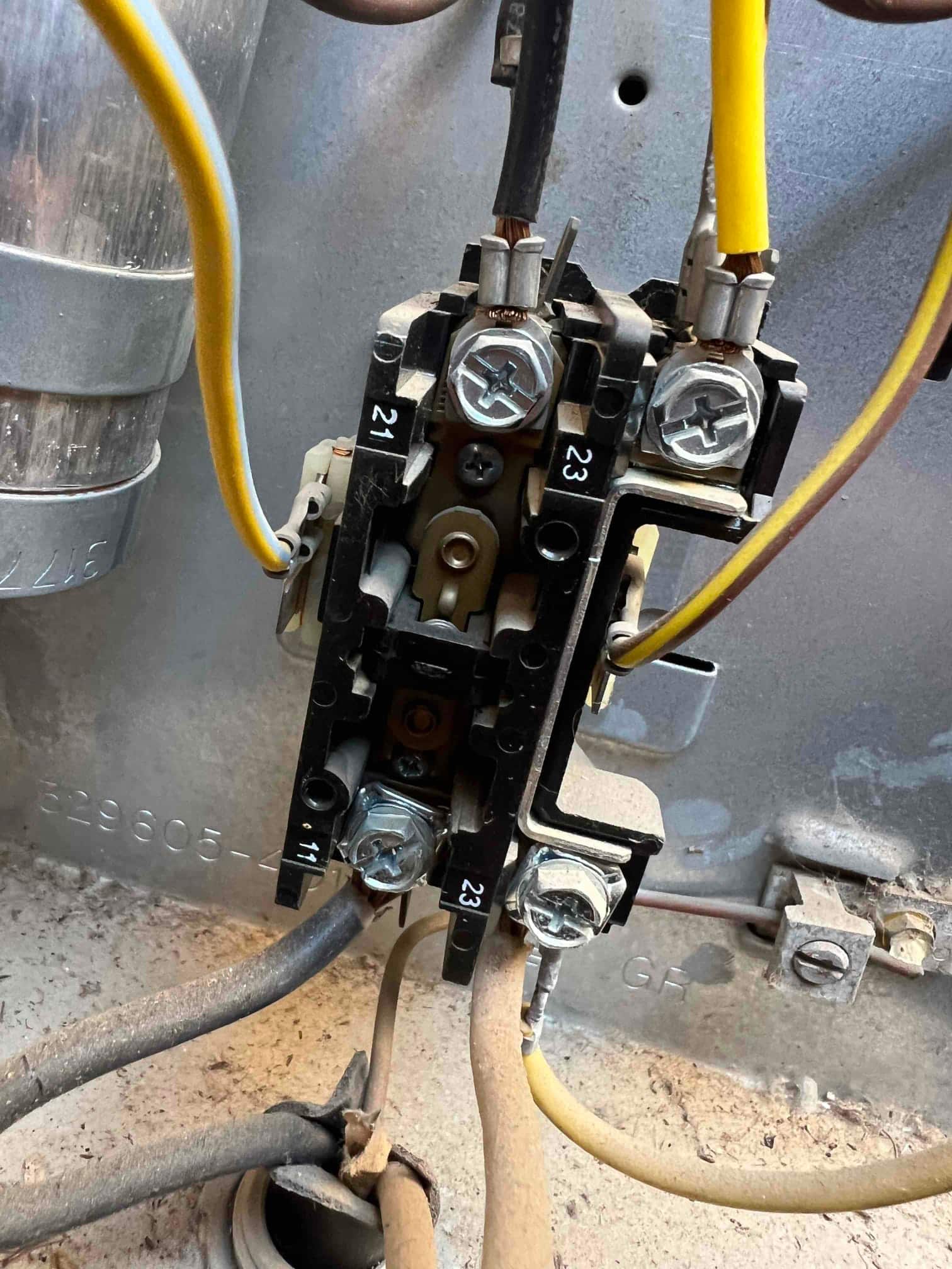Contactor inside condenser cabinet showing wired screw terminals and exposed copper at two connections, with labels 21, 23, and 11.