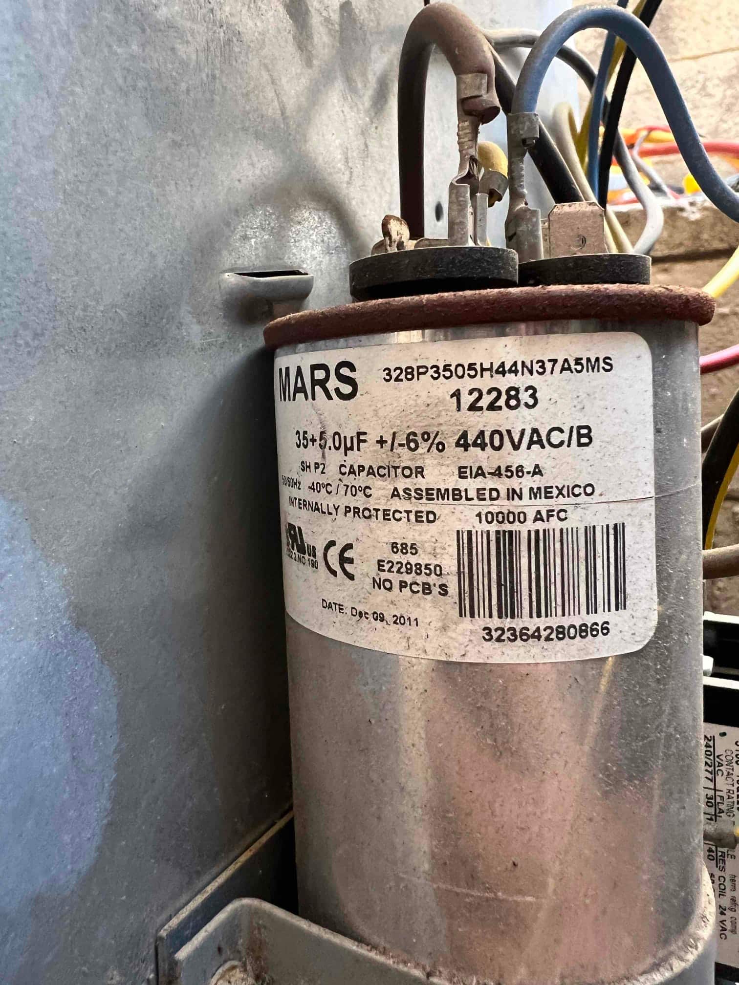 Dual-run capacitor labeled 35+5 μF ±6% 440VAC with connected wiring on the top terminals inside the condenser.