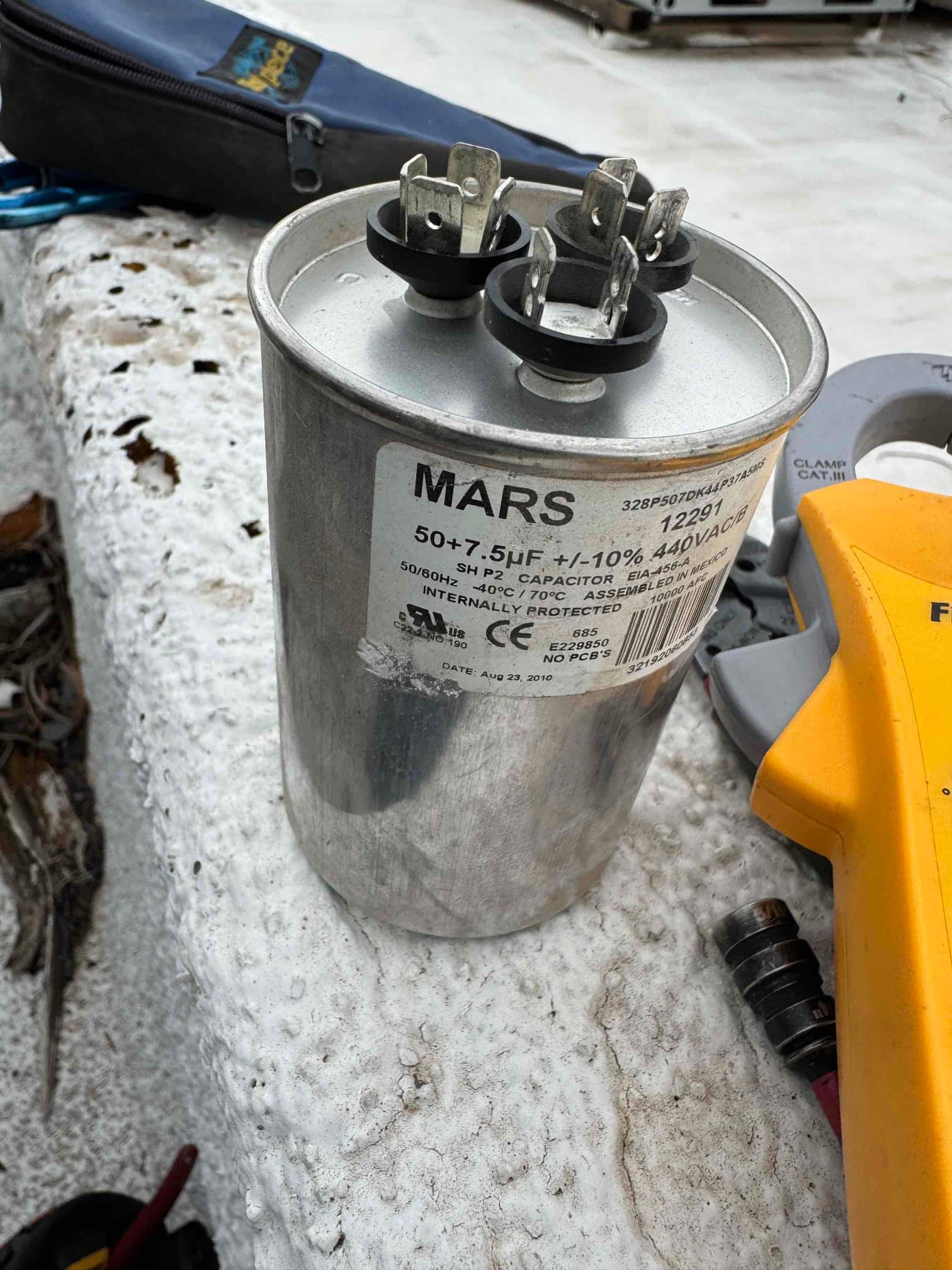 Dual-run capacitor labeled 50+7.5 μF ±10% 440VAC with three terminal posts visible on top.