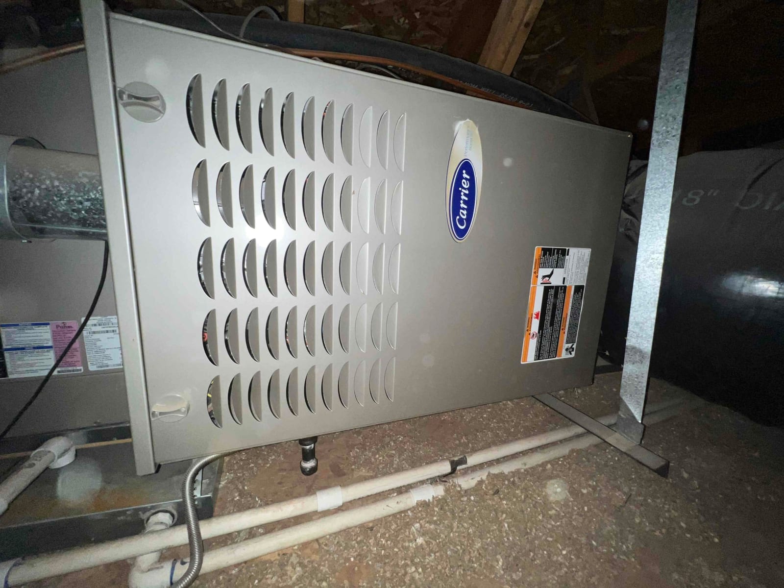 Horizontal furnace cabinet in attic space with louvered panel, vent connection, and condensate drain piping visible.