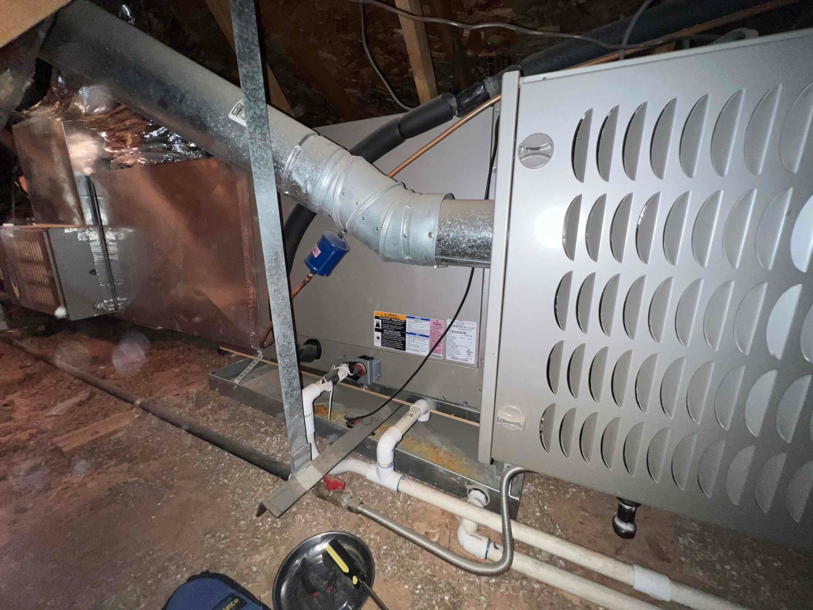 Horizontal furnace and evaporator coil assembly in attic, showing sheet metal ductwork, condensate drain piping, and auxiliary drain pan.