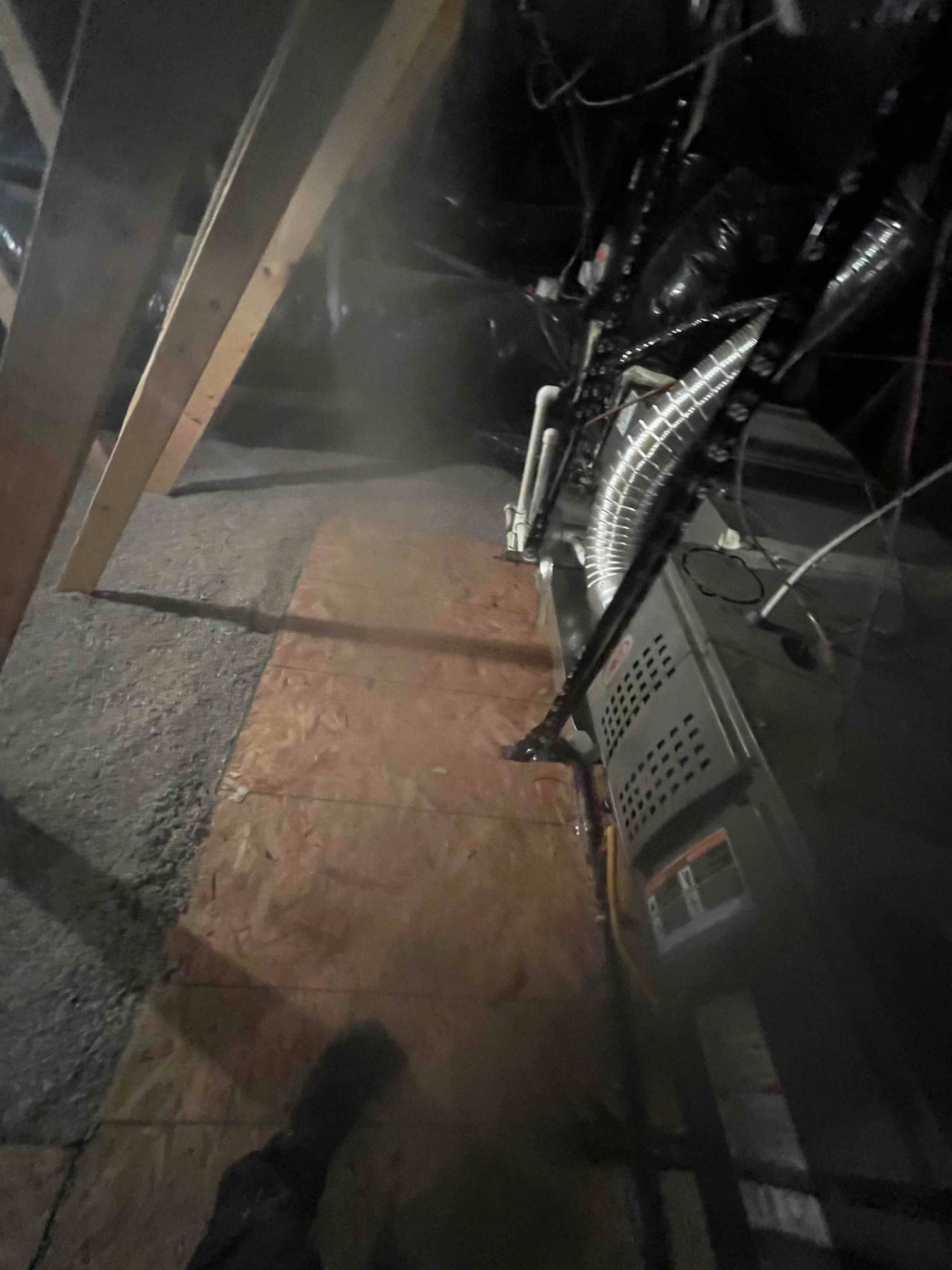 Horizontal furnace and evaporator coil in attic with flexible duct connections, PVC condensate piping, and mounting brackets visible along the platform.