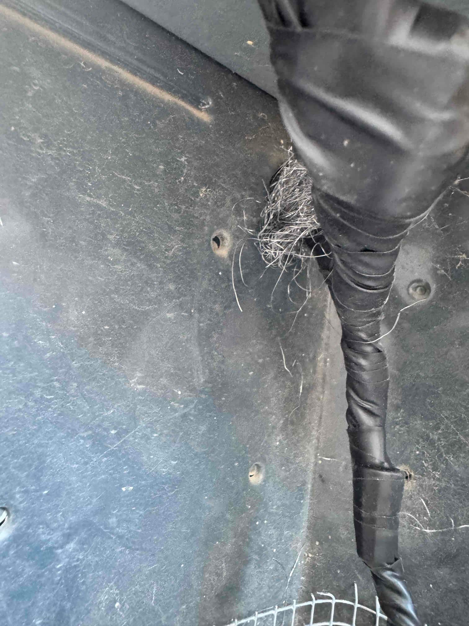 Interior cabinet panel shows a black-wrapped line passing through, with a bundle of fine metal strands at the penetration.