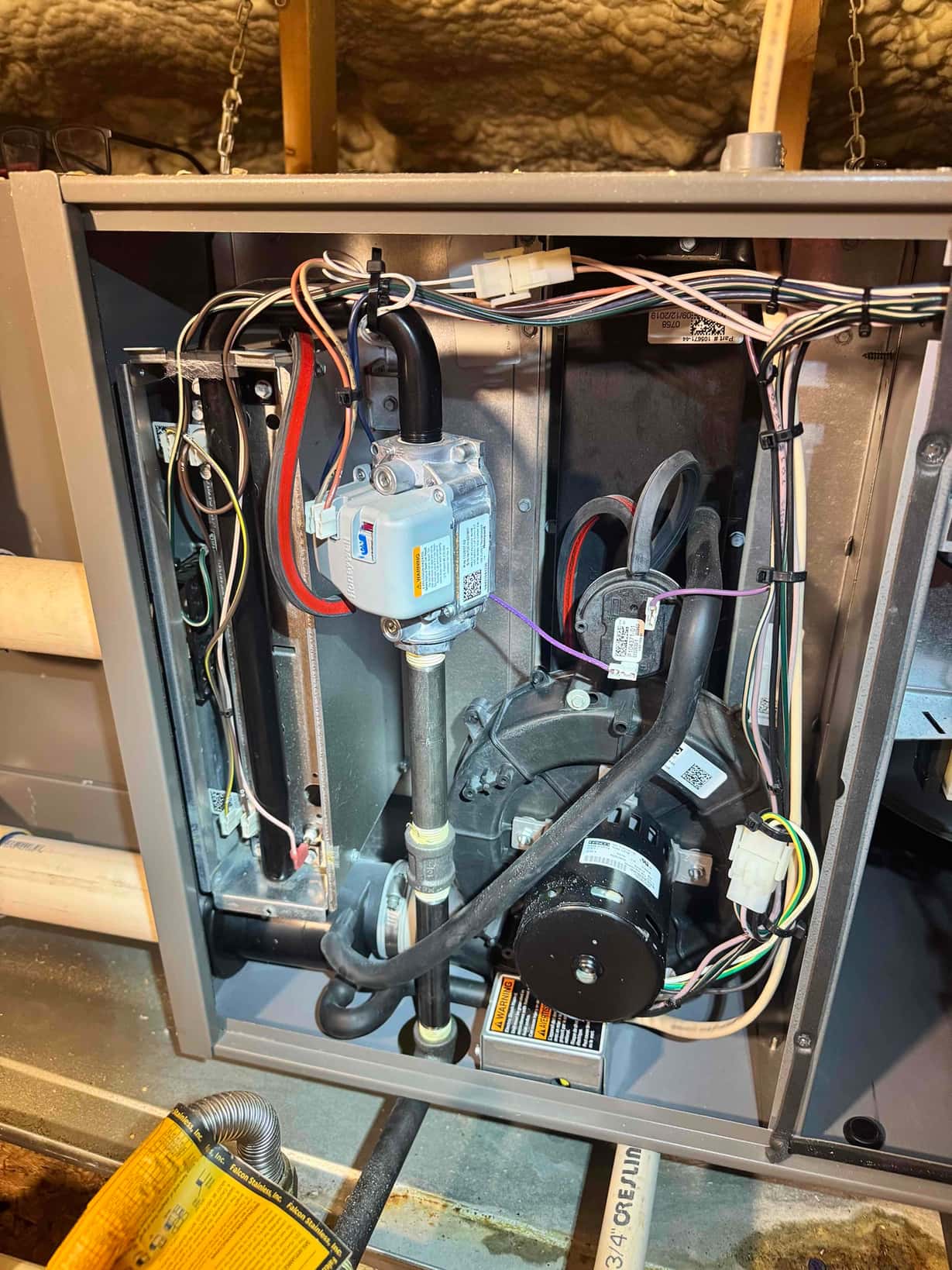 Open gas furnace cabinet shows gas valve, burner compartment, draft inducer motor, control wiring, and condensate drain tubing.