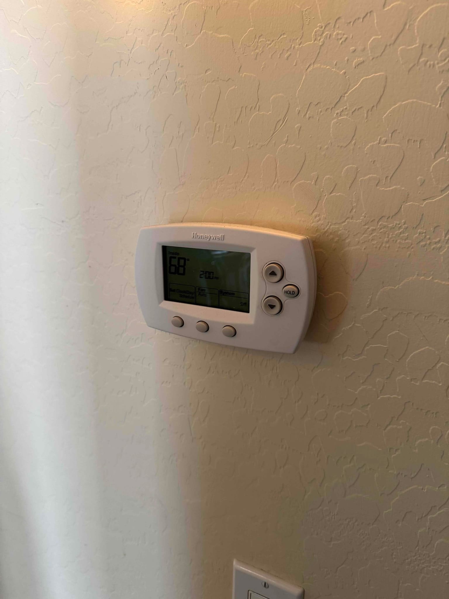 Wall-mounted digital thermostat displays 68°F inside temperature with control buttons and backlit screen.