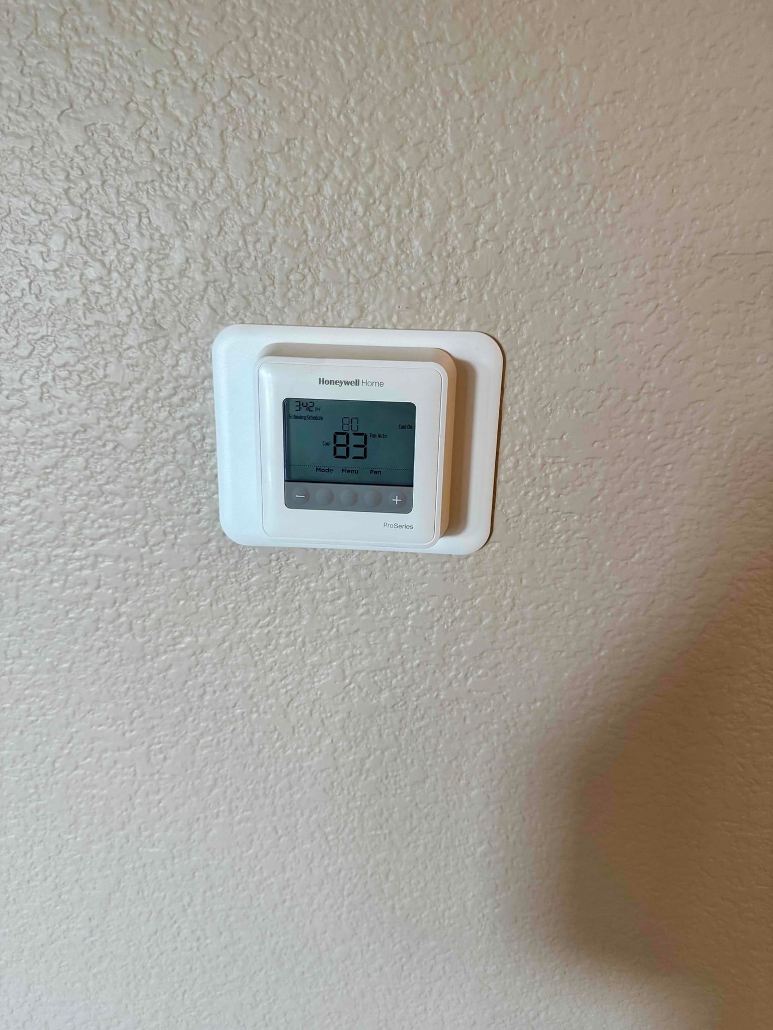 Wall-mounted digital thermostat display shows 83°F room temperature and 80°F cooling setpoint.