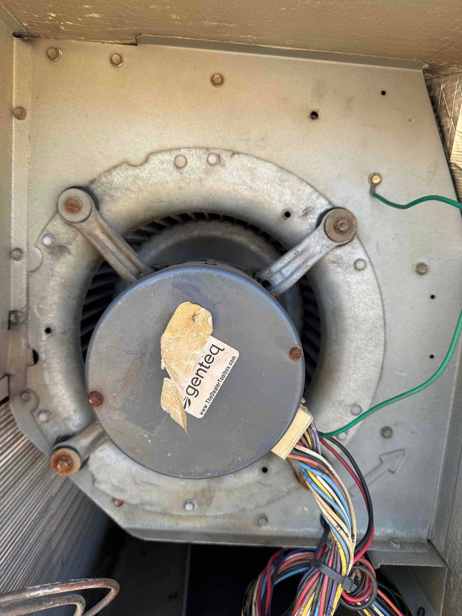 Blower assembly inside the air handler, with motor, mounting arms, visible blower wheel, and multi-color wiring harness.