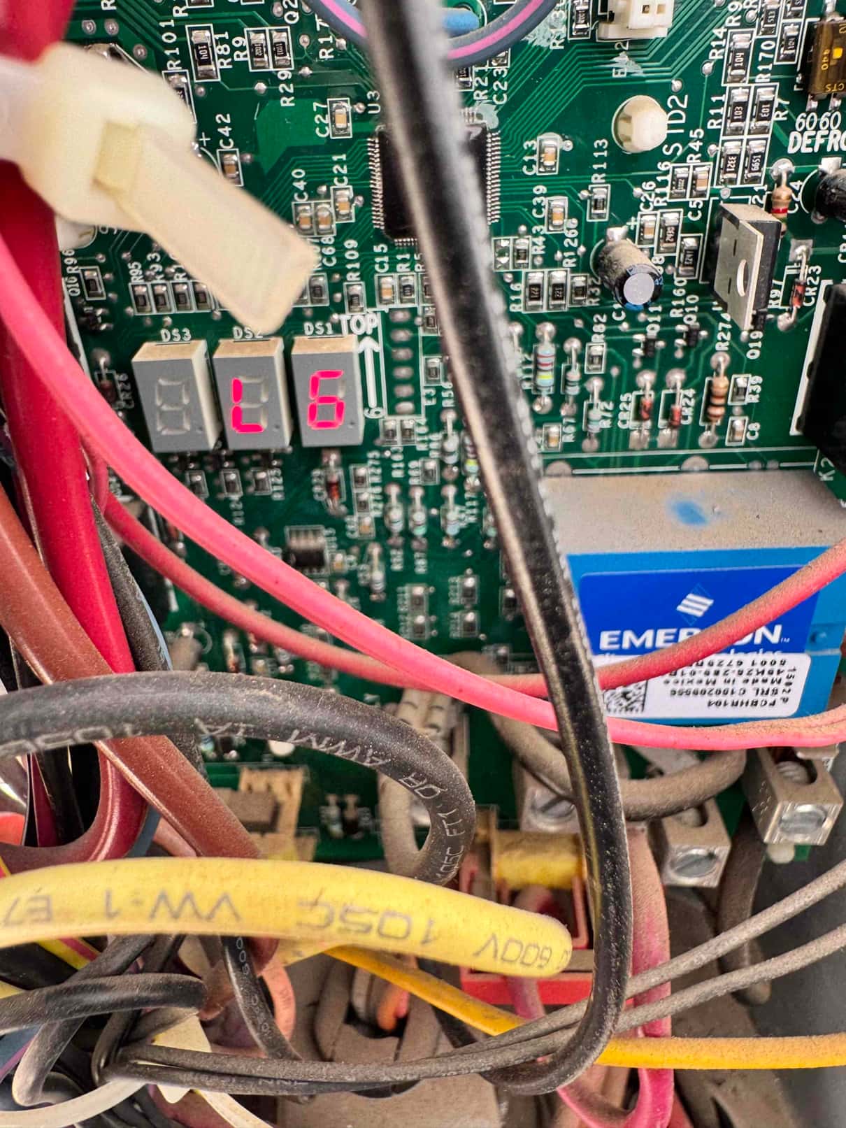 Control board inside equipment cabinet with red and yellow wiring, showing two-digit status display reading L and 6.