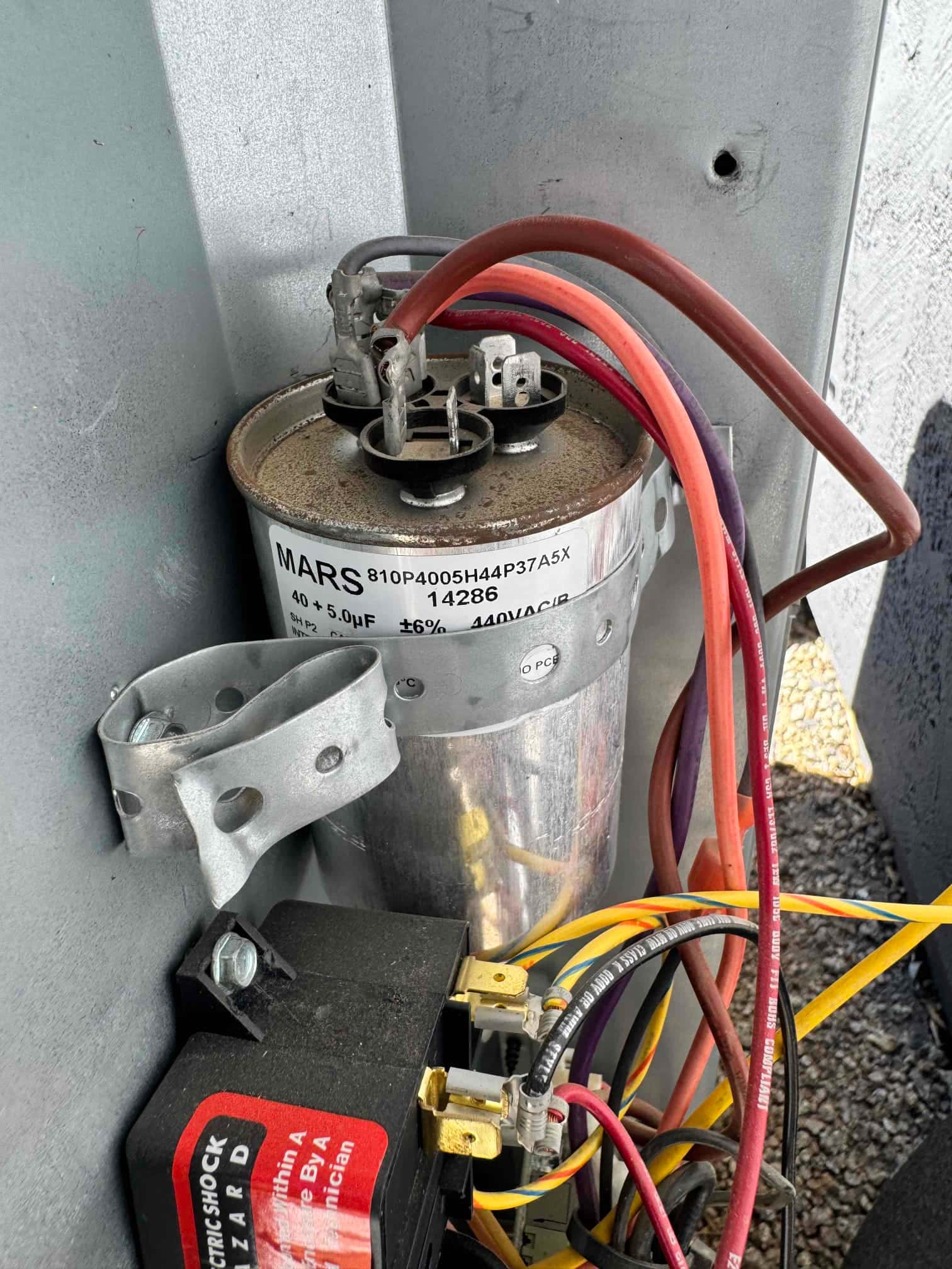 Dual-run capacitor labeled 40 + 5.0 μF, 440VAC, with wires connected to terminals and light rust on the top.