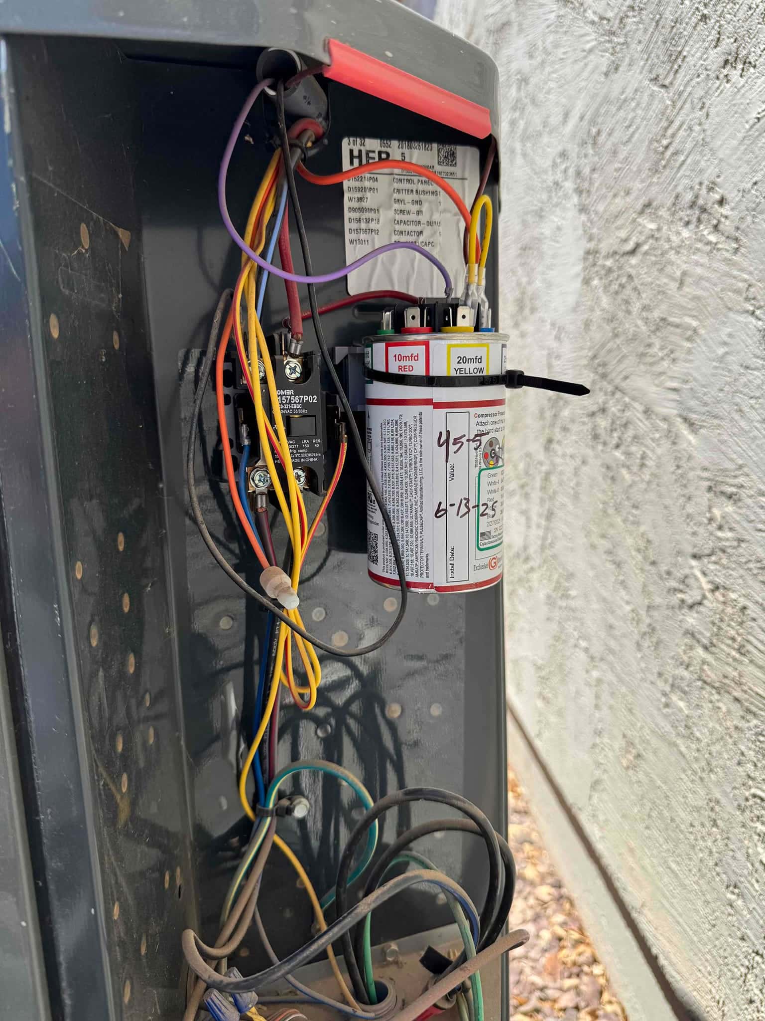 Multi-tap run capacitor with labeled 10 mfd red and 20 mfd yellow terminals wired in the condenser control panel.