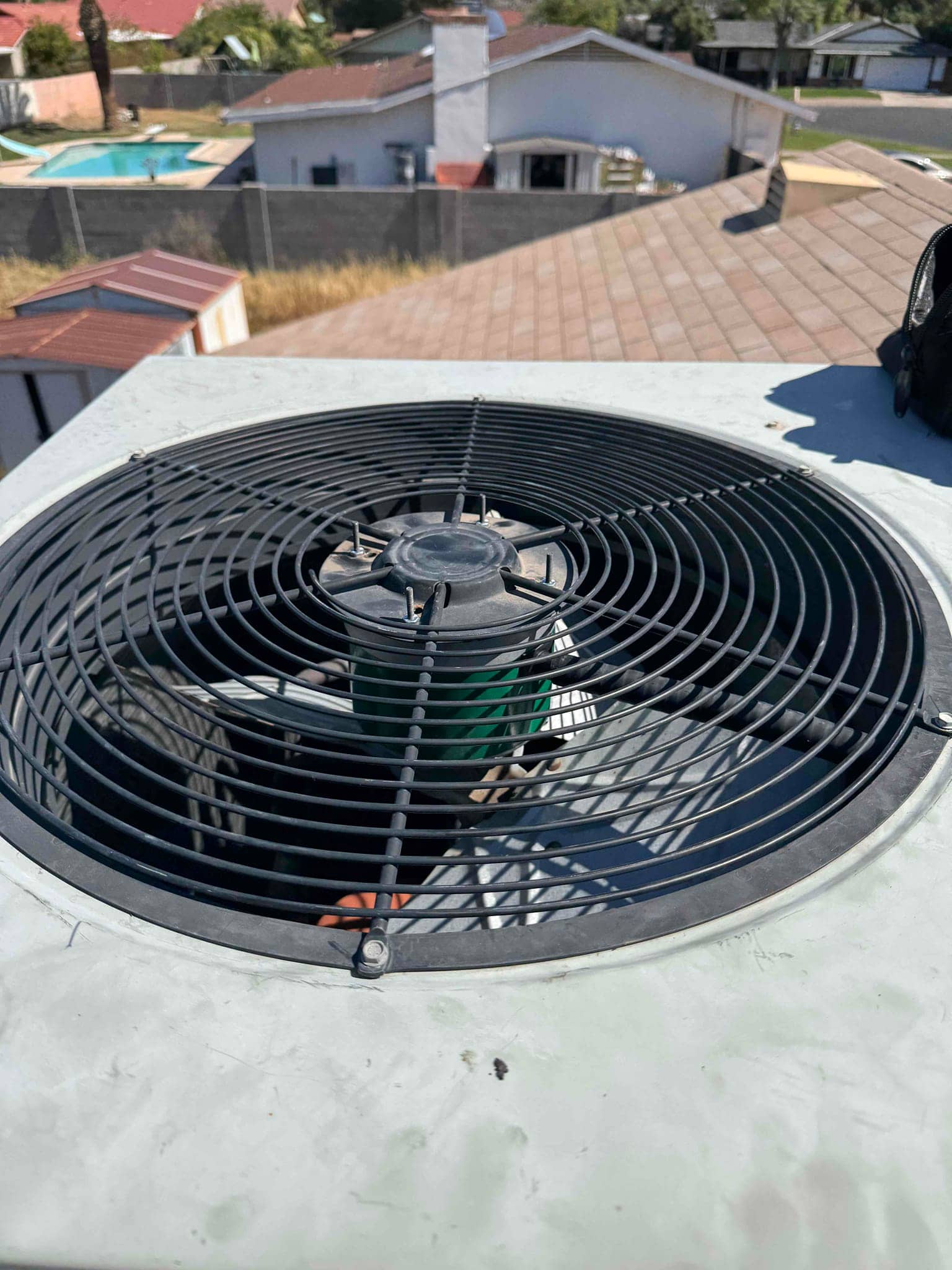 Top view of rooftop condenser showing protective fan grille and the central fan motor inside the housing.