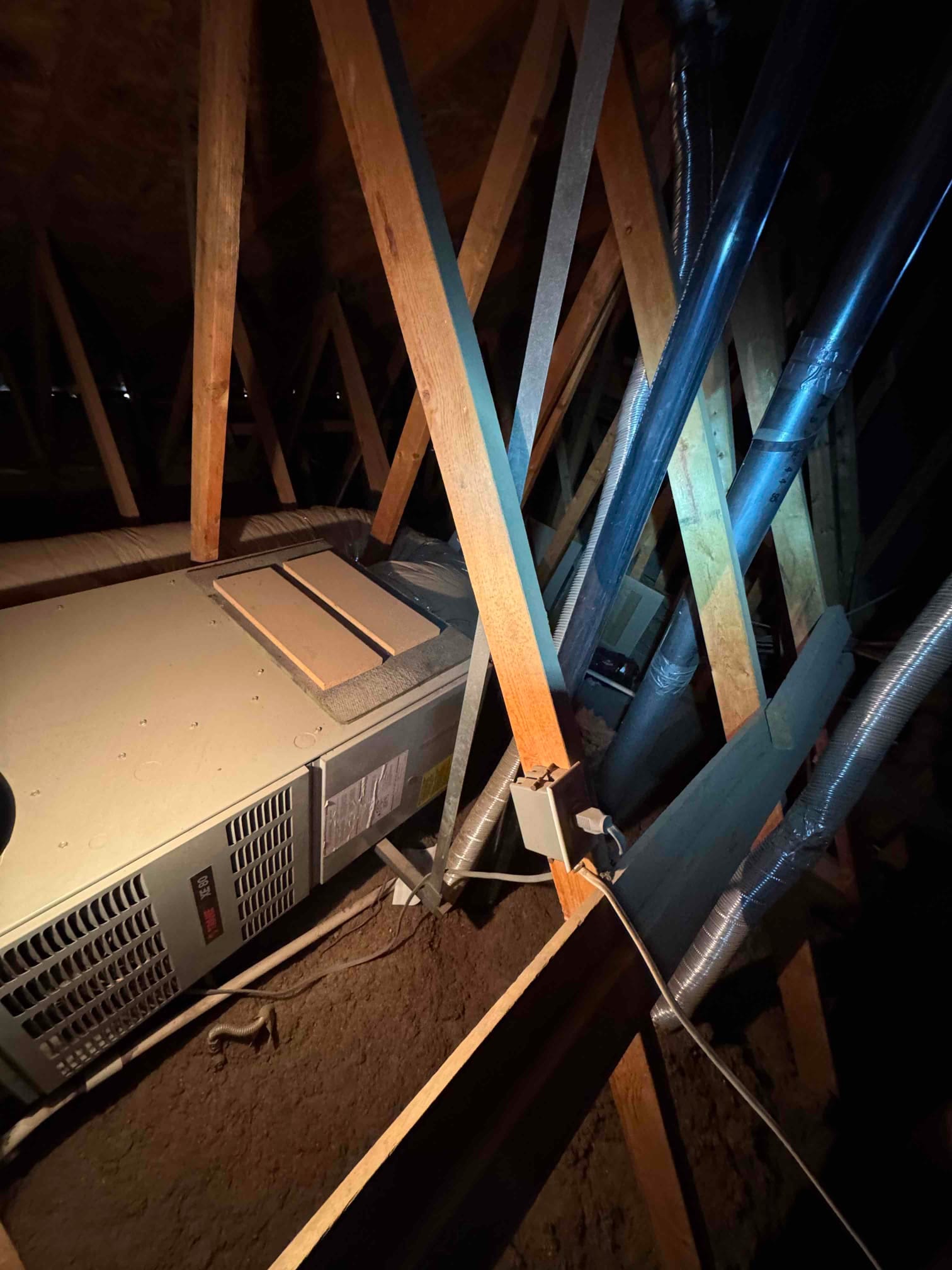 Attic horizontal air handler with flex duct connections, drain line, and nearby electrical box visible.