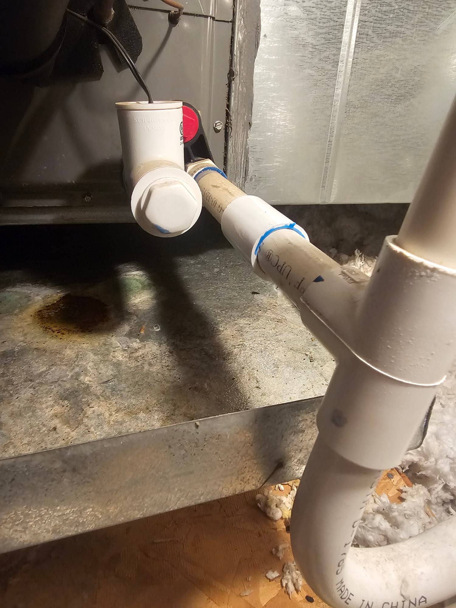 Condensate drain assembly with PVC tees, cleanout caps, and a wired condensate safety switch at the air handler.