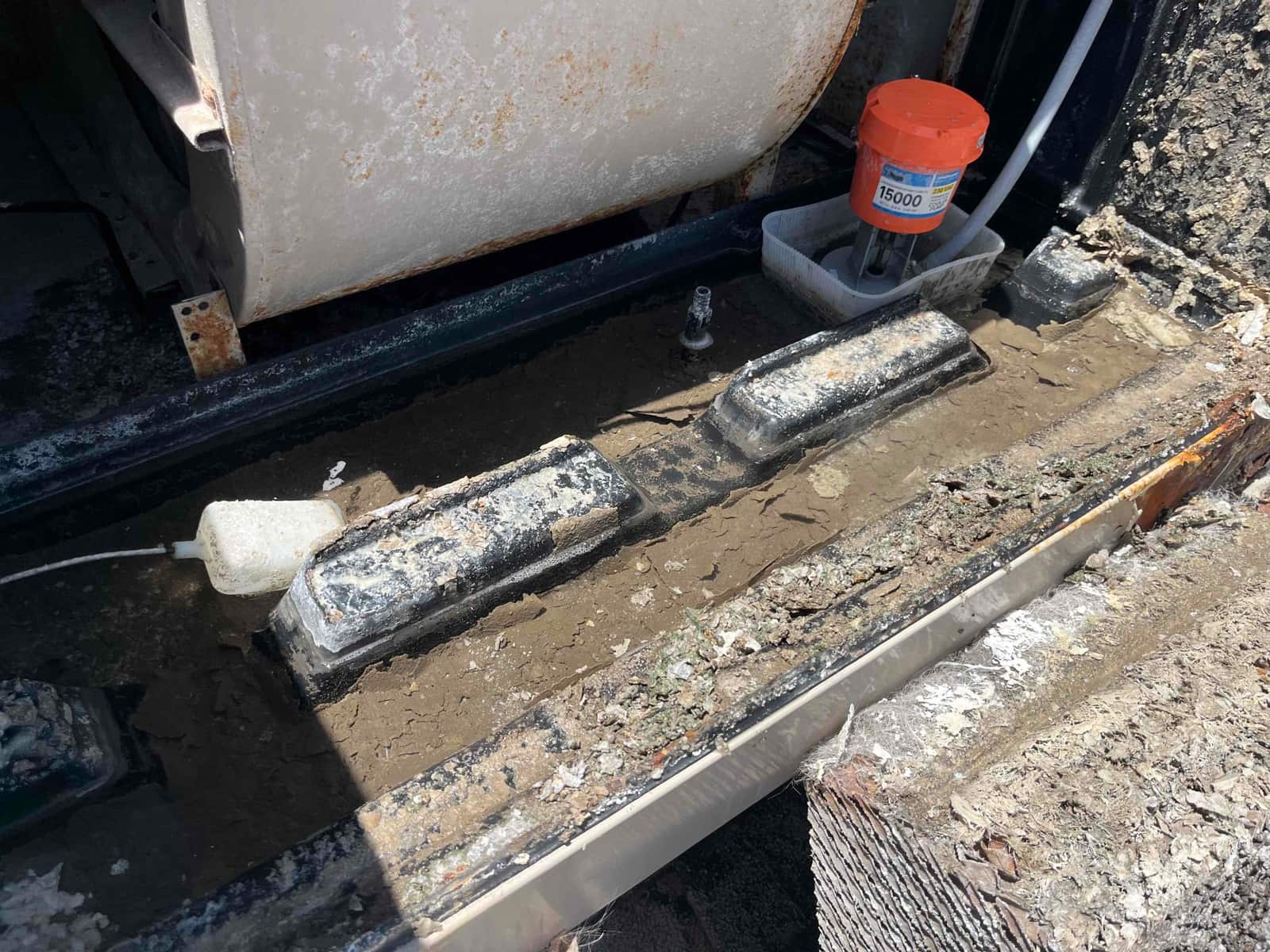 Drain pan inside air handler shows heavy sludge and debris, with a float switch and treatment device present.