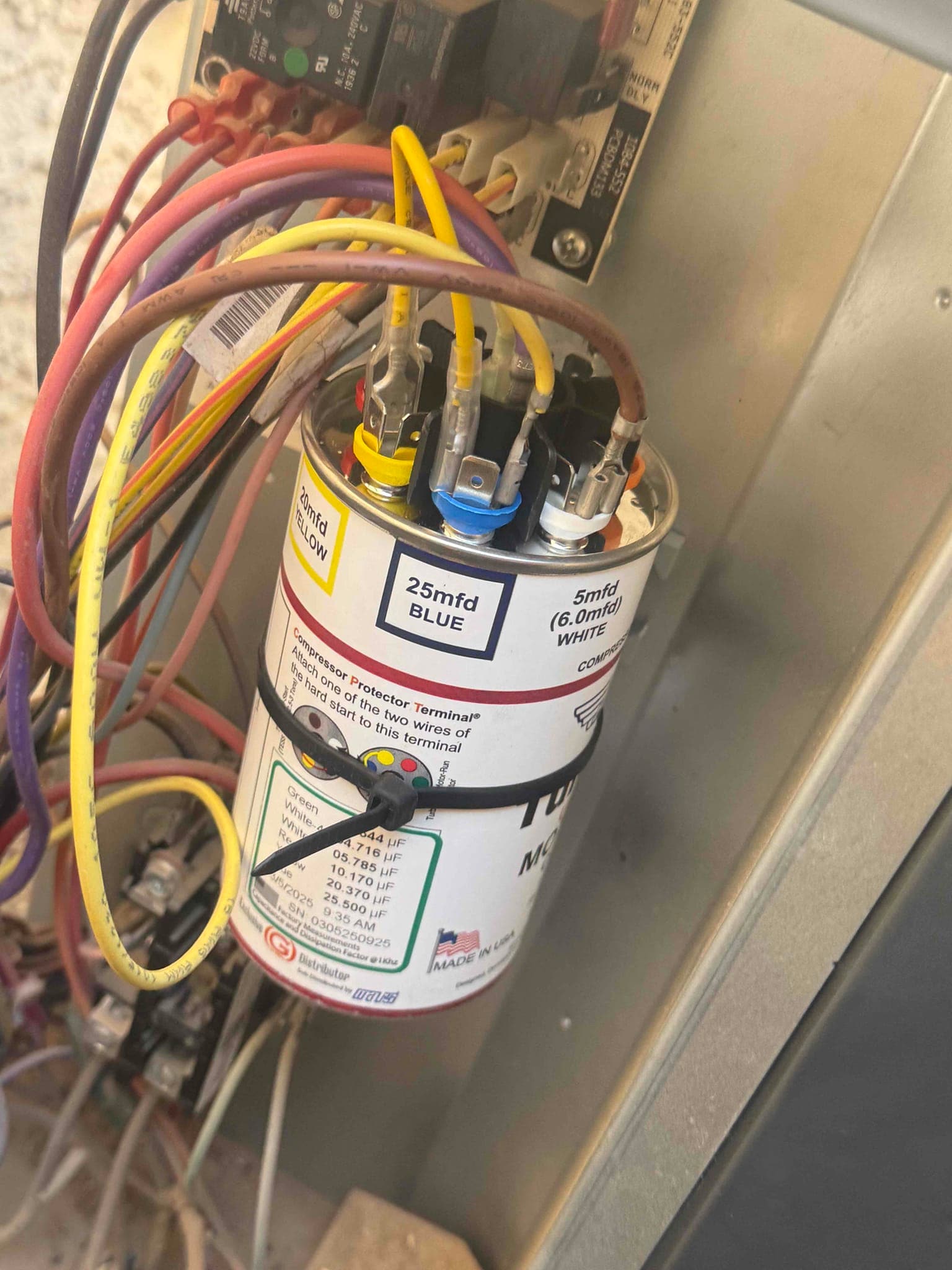 Dual-run capacitor labeled 25 mfd BLUE and 5 mfd WHITE, with yellow and brown wires connected to its terminals.