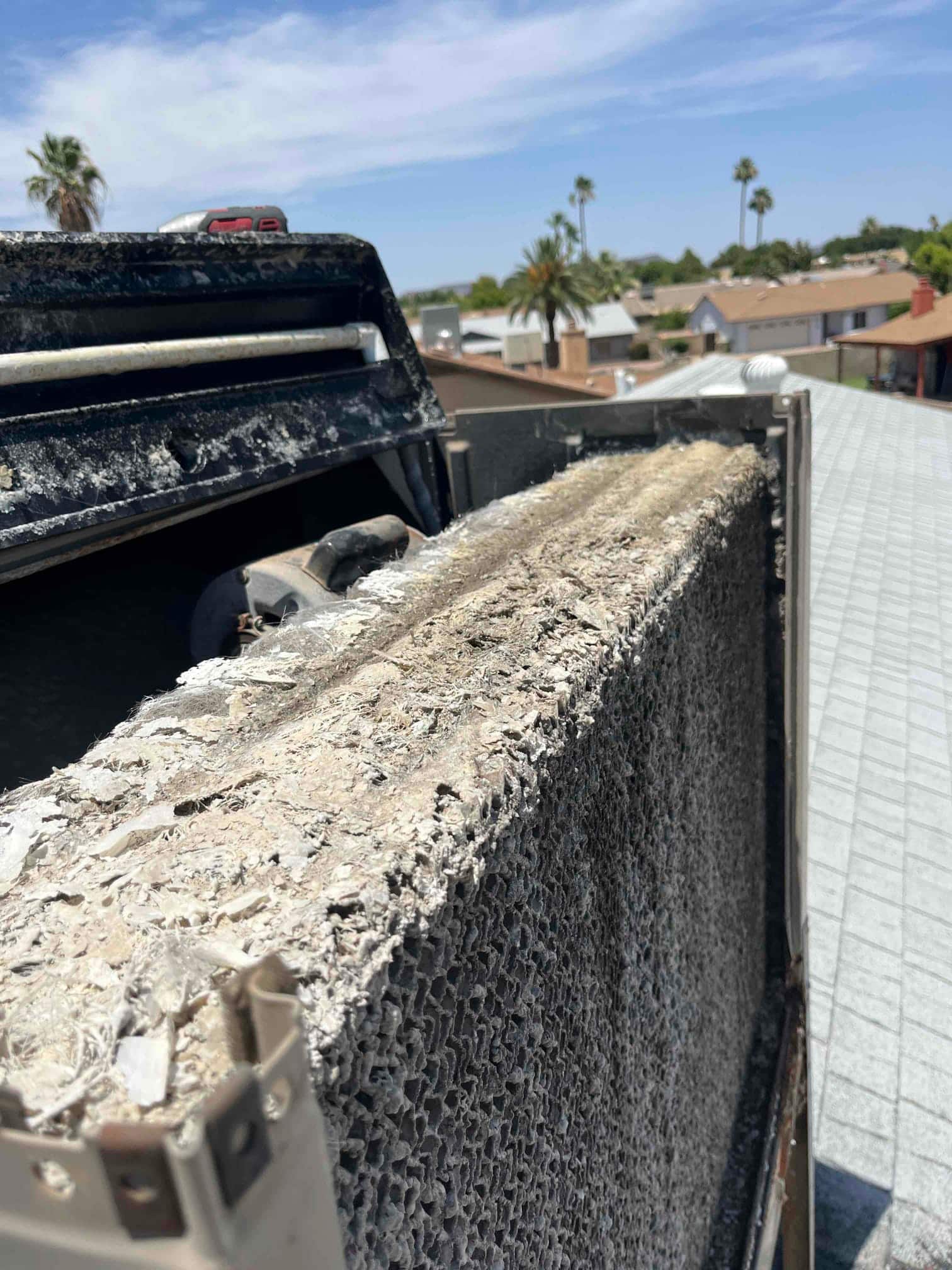 Evaporative cooler media pad shows heavy mineral and debris buildup along the surface inside the rooftop unit.