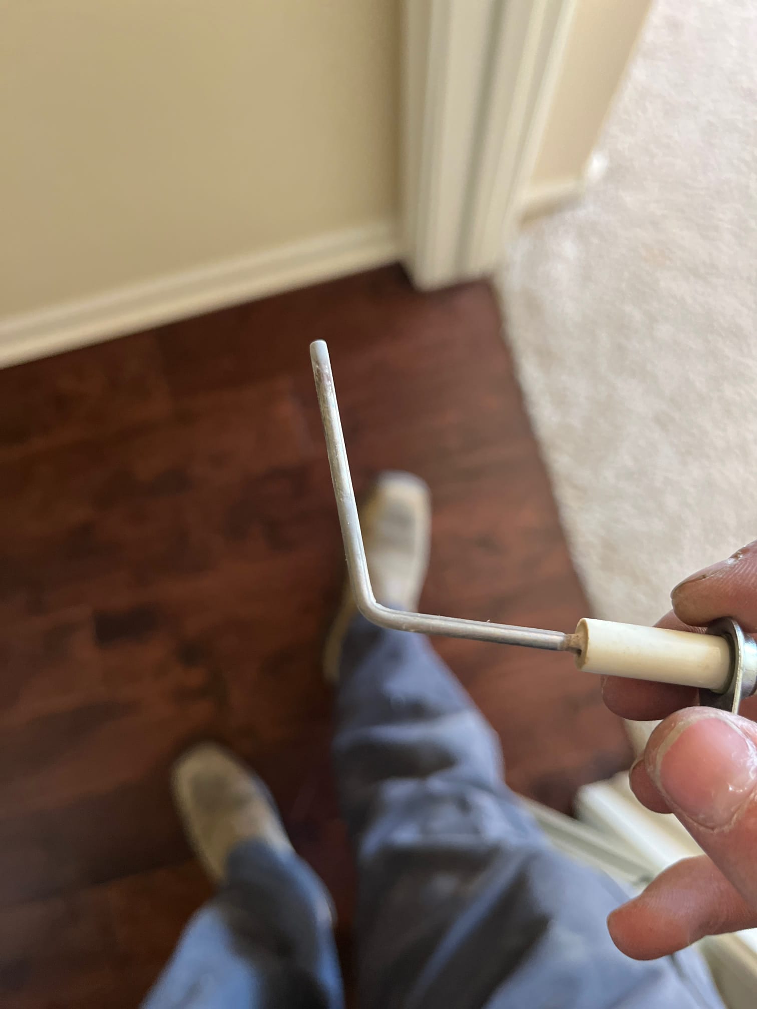 Flame sensor with porcelain insulator held by a technician, showing the L-shaped sensing rod and mounting bracket.